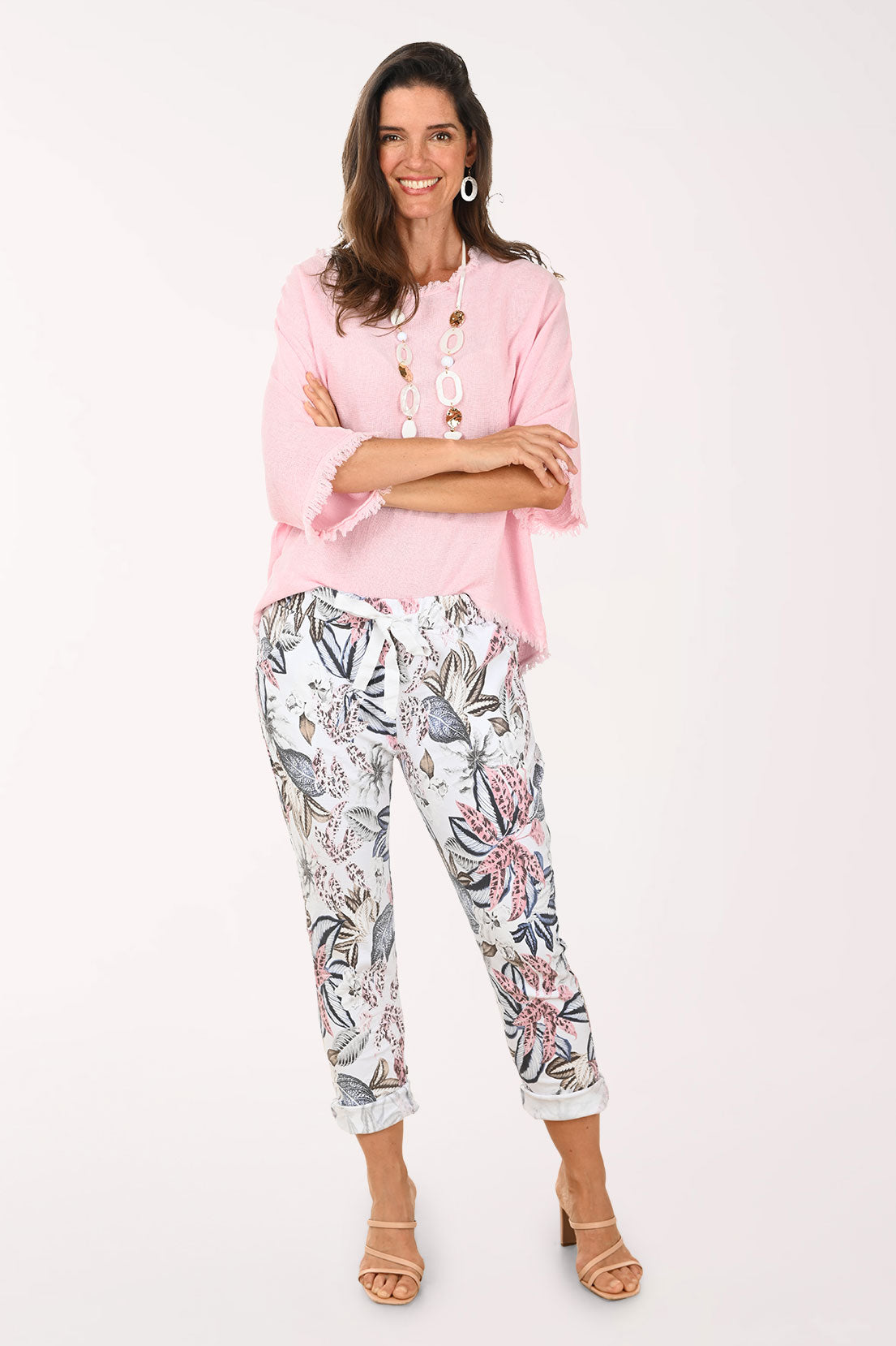 Woman wearing a pink blouse and floral pants on a white background