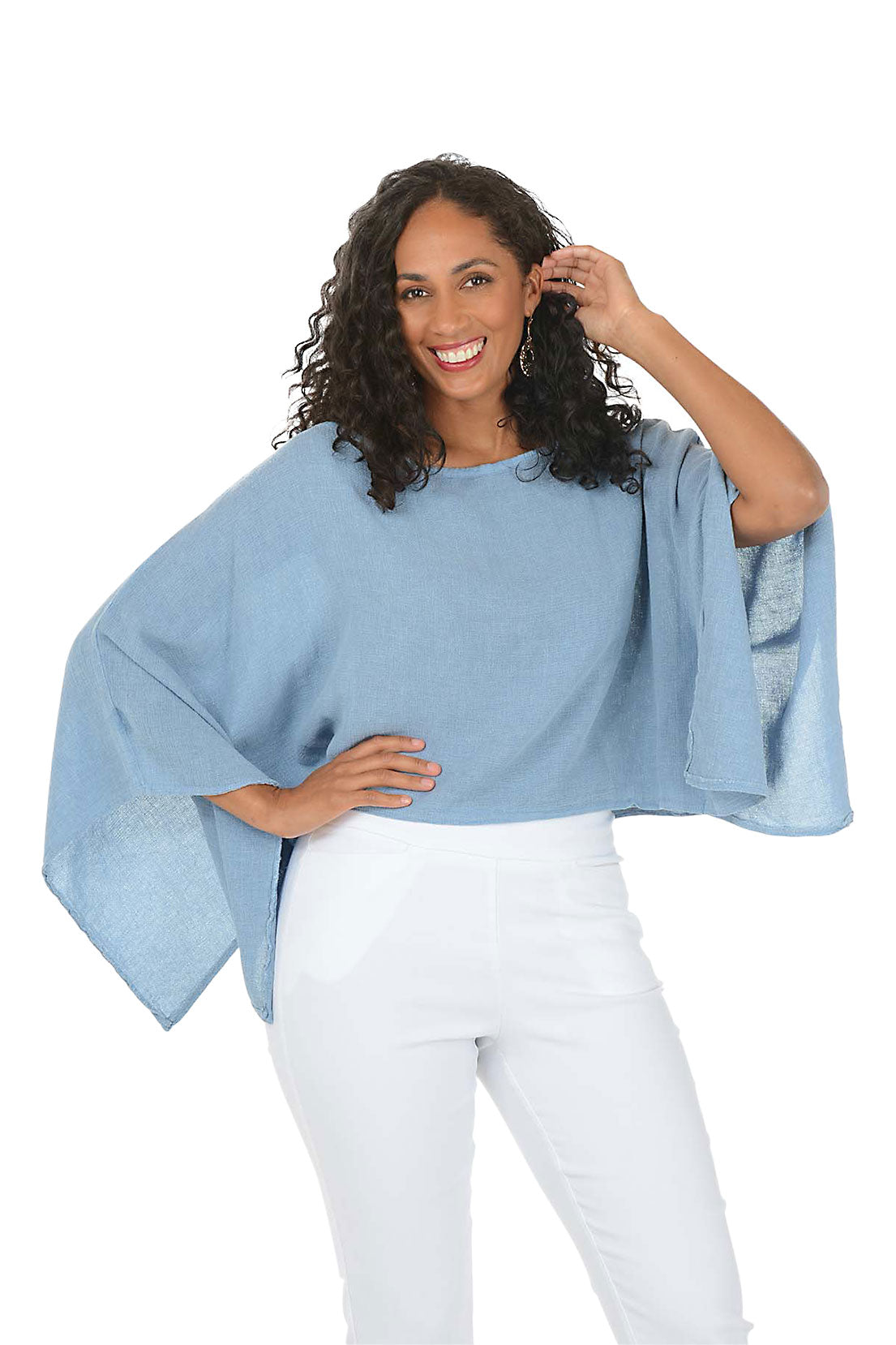 Woman wearing a blue sweater and white pants on a white background. Second front shot.
