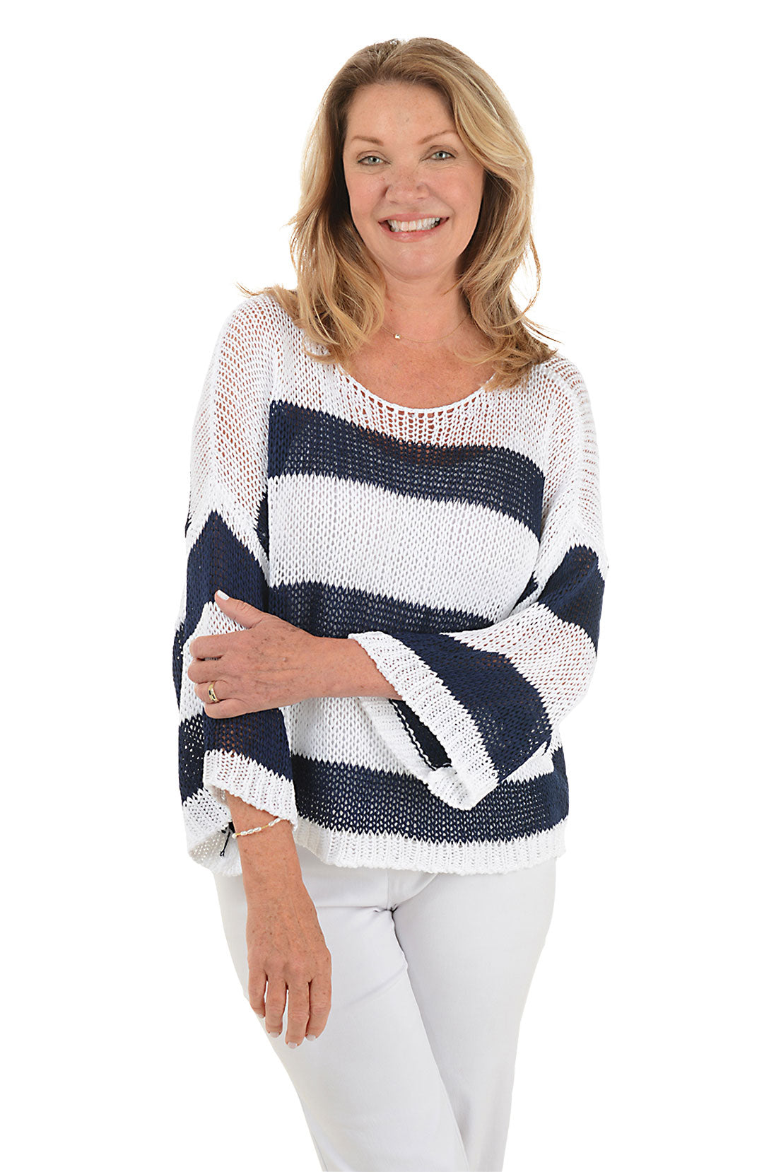 A front shot of a model wearing a white and navy striped dolman sleeve open weave sweater with a scoop neck.