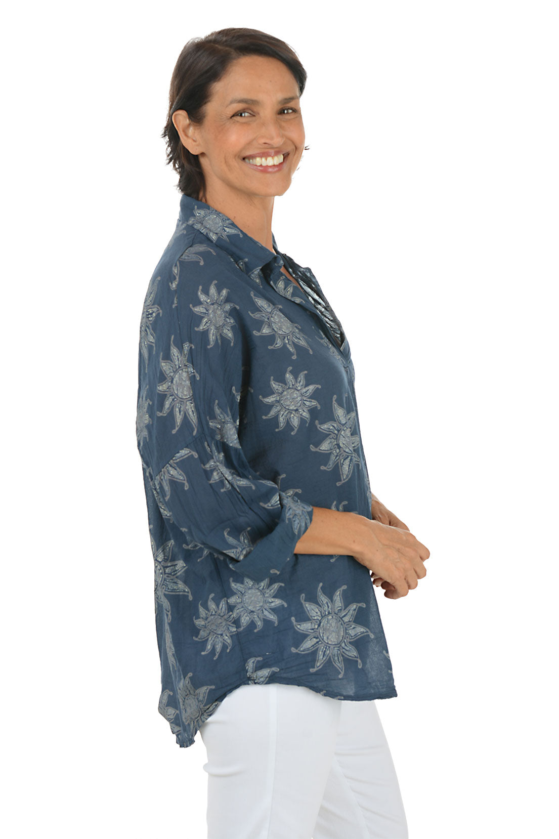 Woman wearing a blue floral patterned shirt on a white background. Side shot.
