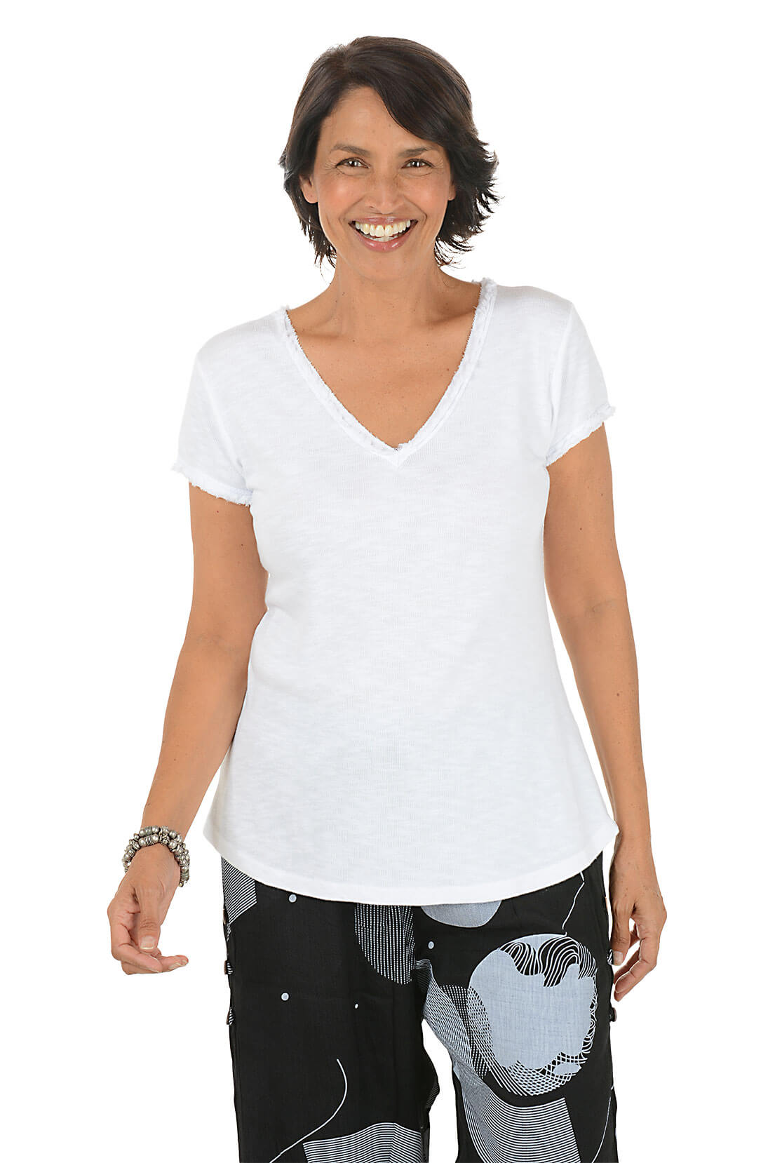 Woman wearing a white V-neck t-shirt and patterned pants on a white background