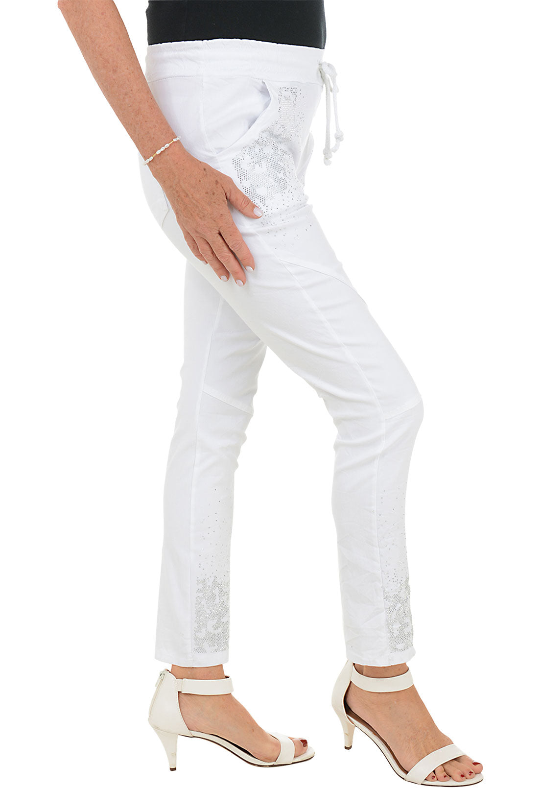 A side shot of a model wearing a white Jegging with leopard rhinestone embellishment, featuring a slim leg design, dual front and back pockets, and an adjustable drawstring waistband.