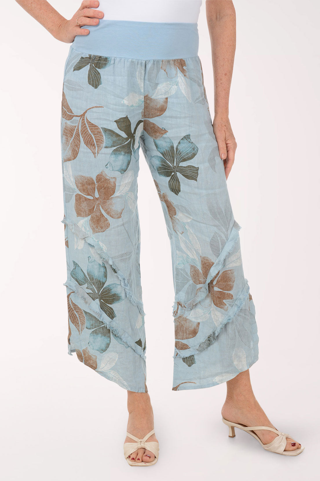 Woman wearing blue flowy pants with printed flowers.