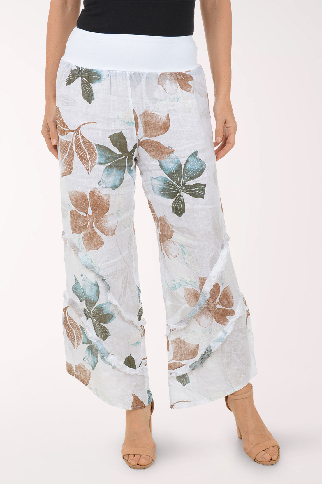 Woman wearing white flowy pants with printed flowers.