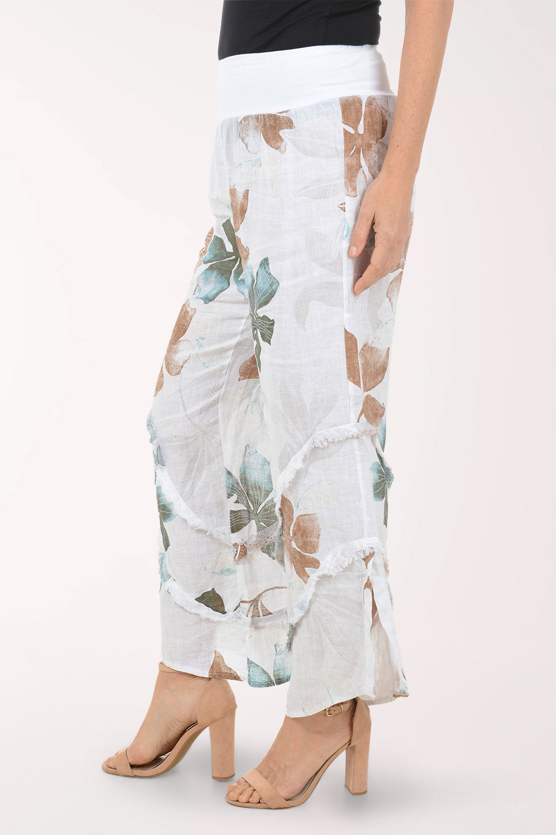 Woman wearing white flowy pants with printed flowers.