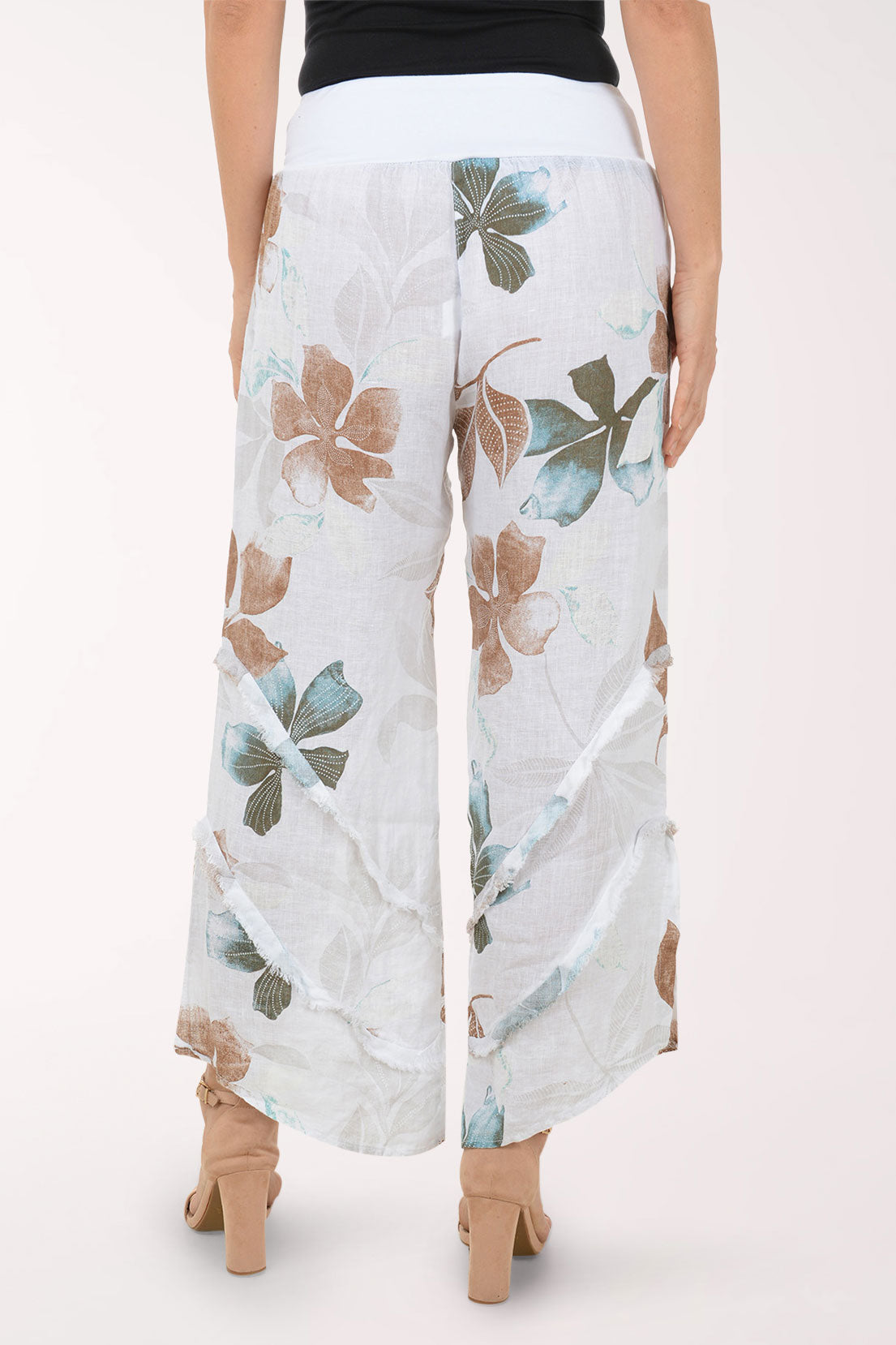 Woman wearing white flowy pants with printed flowers.