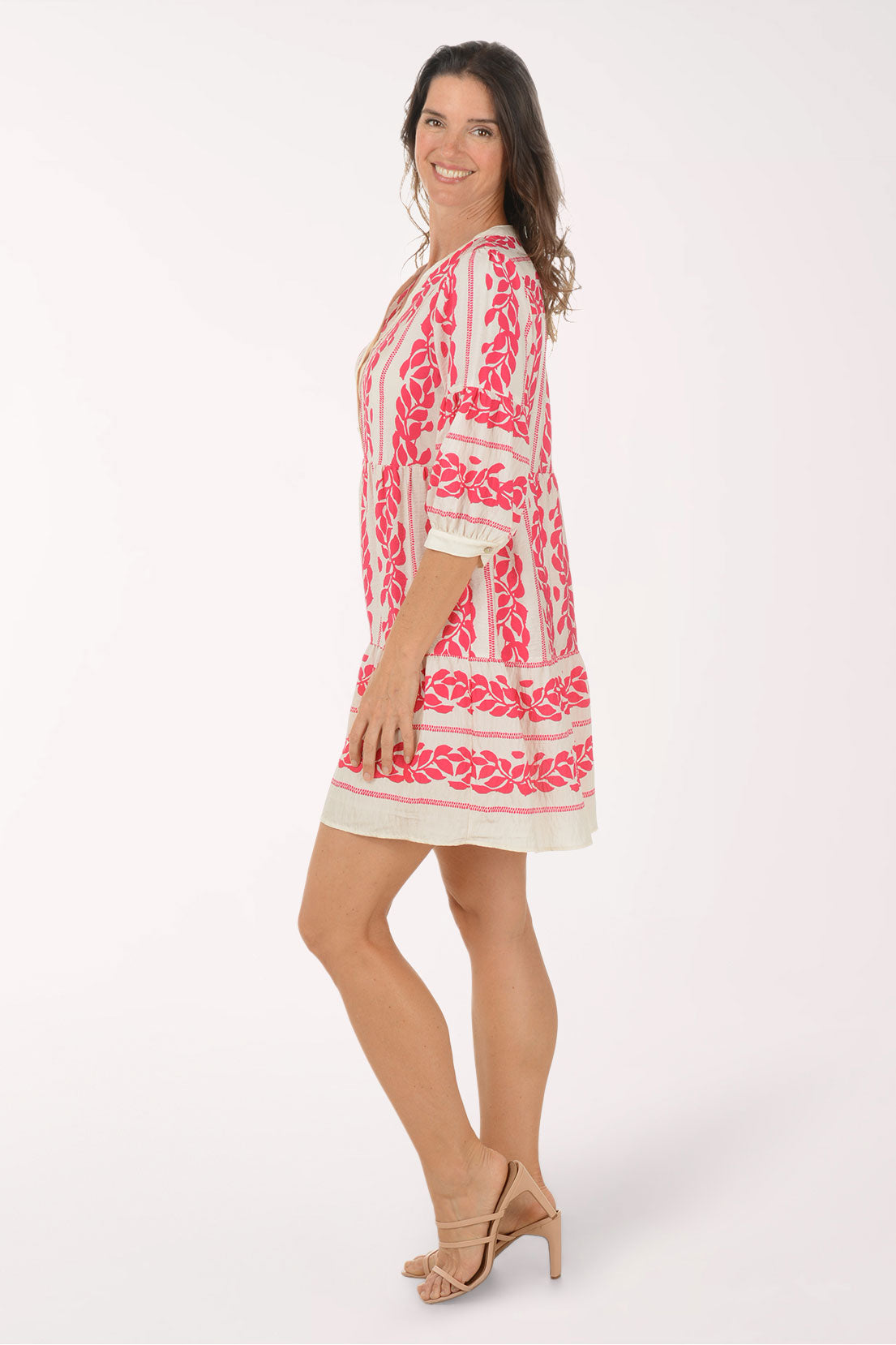 Woman wearing a pink and white embroidered dress on a white background