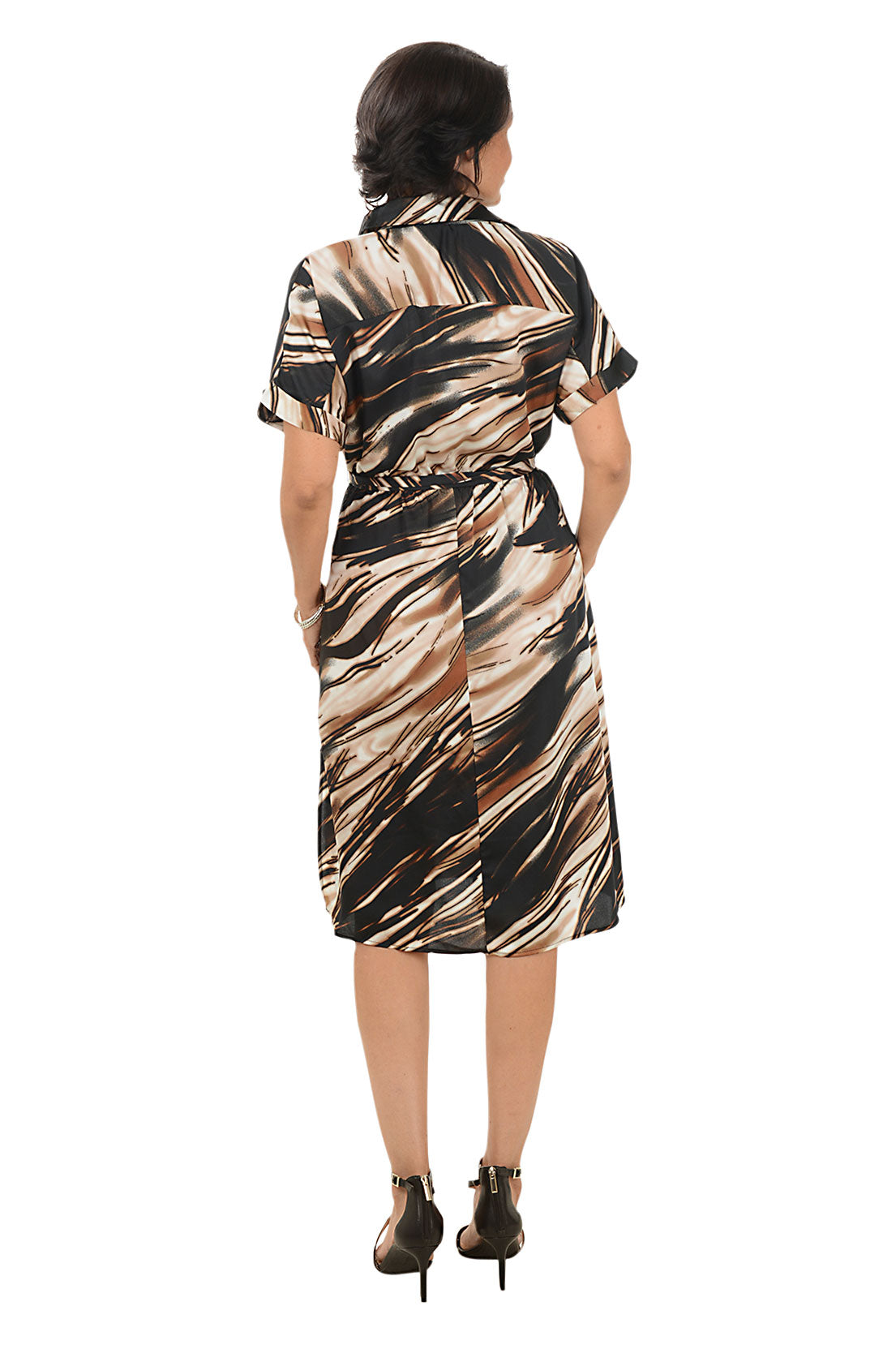 Woman wearing a brown patterned dress on a white background. Back shot.