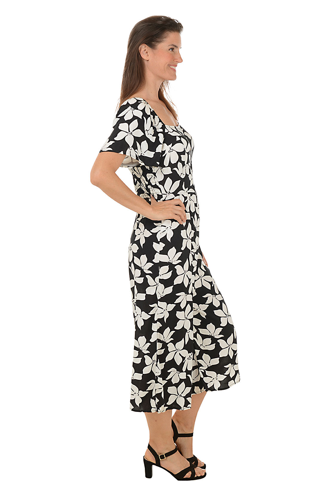 A side shot of a model wearing a square neck, floral print jumpsuit with short flutter sleeves and a buttoned half placket.