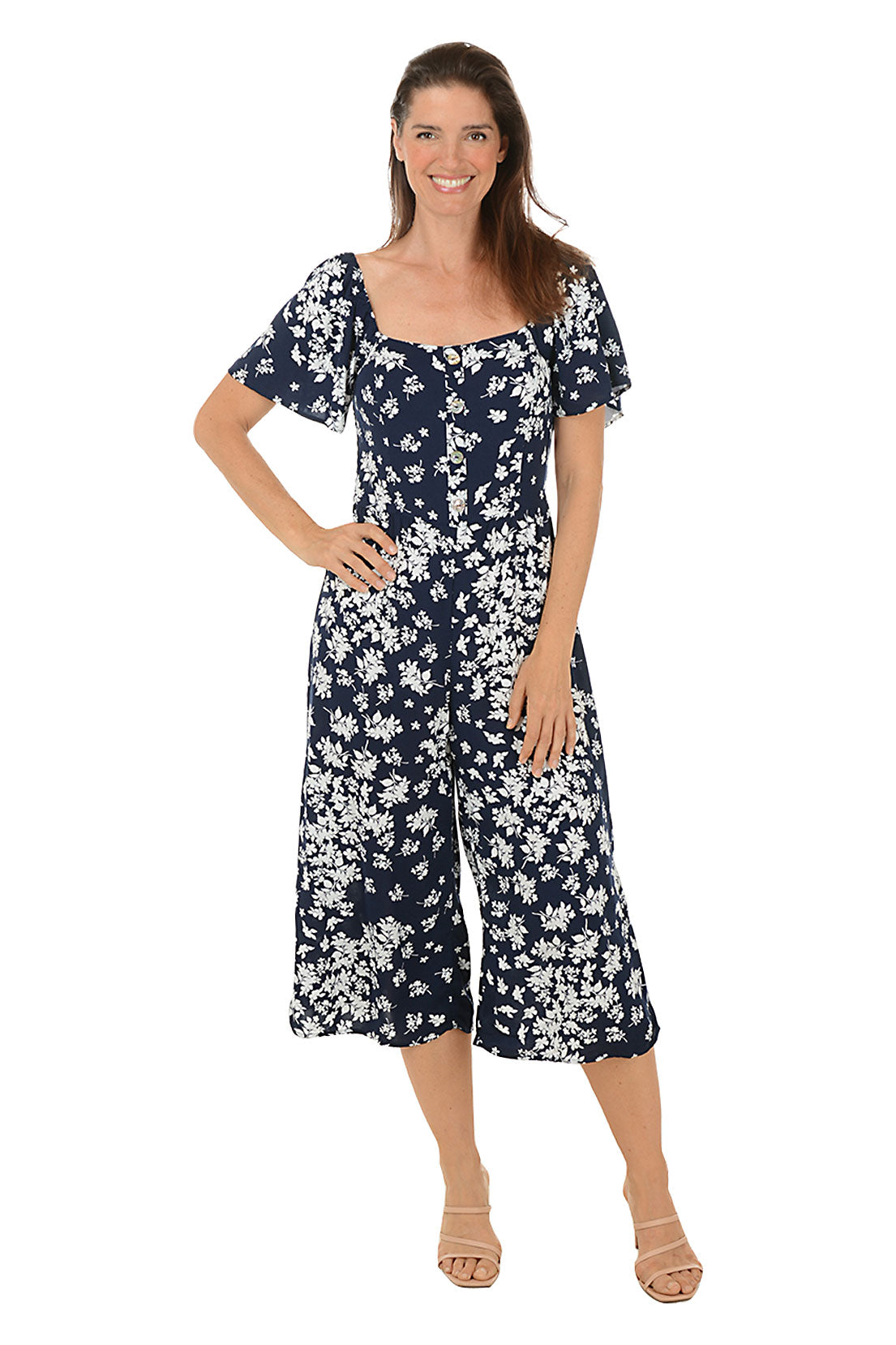 A front shot of a model wearing a navy floral square neck jumpsuit with short flutter sleeves and wide legs.
