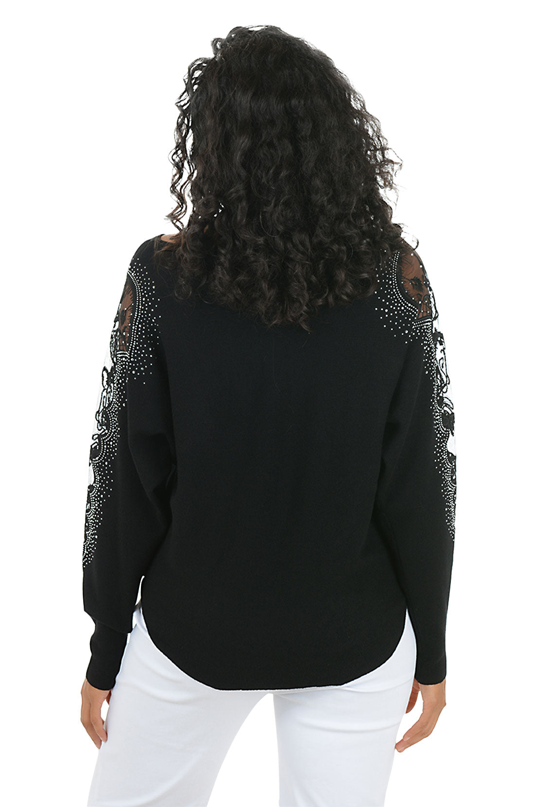 Woman wearing a long sleeve black sweater with scalloped mesh embellishments and rhinestone accents on shoulders. Back shot.