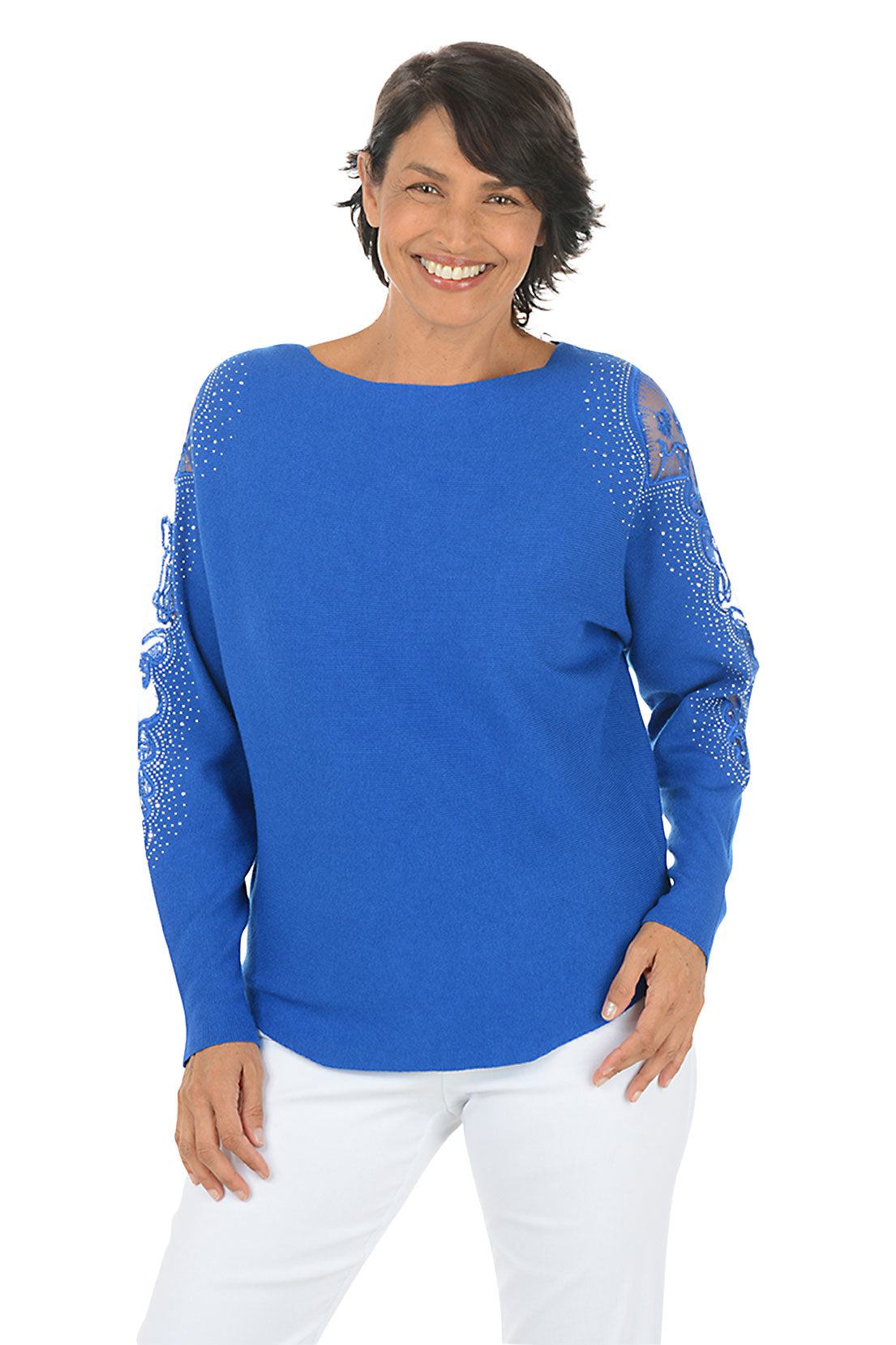 Woman wearing a long sleeve blue sweater with scalloped mesh embellishments and rhinestone accents on shoulders.