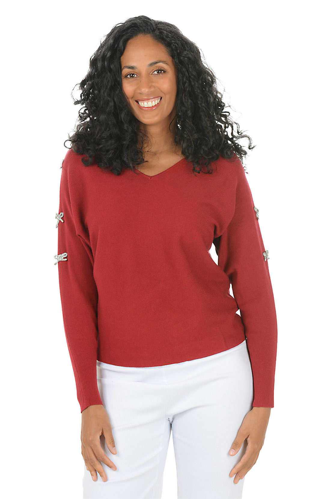 Woman wearing a red sweater with rhinestone bow embellishments on the sleeves on a white background.