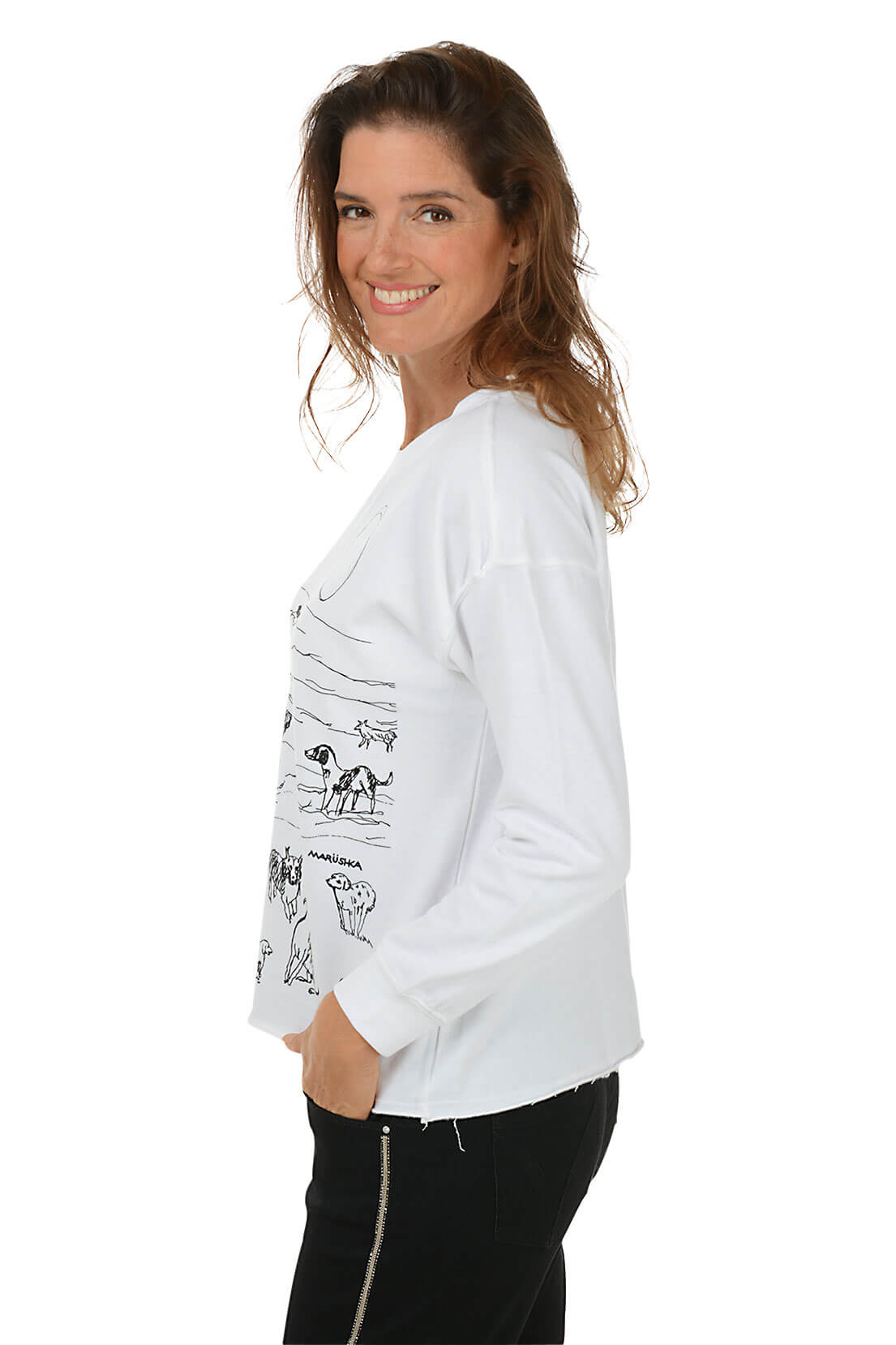 A woman wears a white sweatshirt with a dog print against a white background. Side shot.