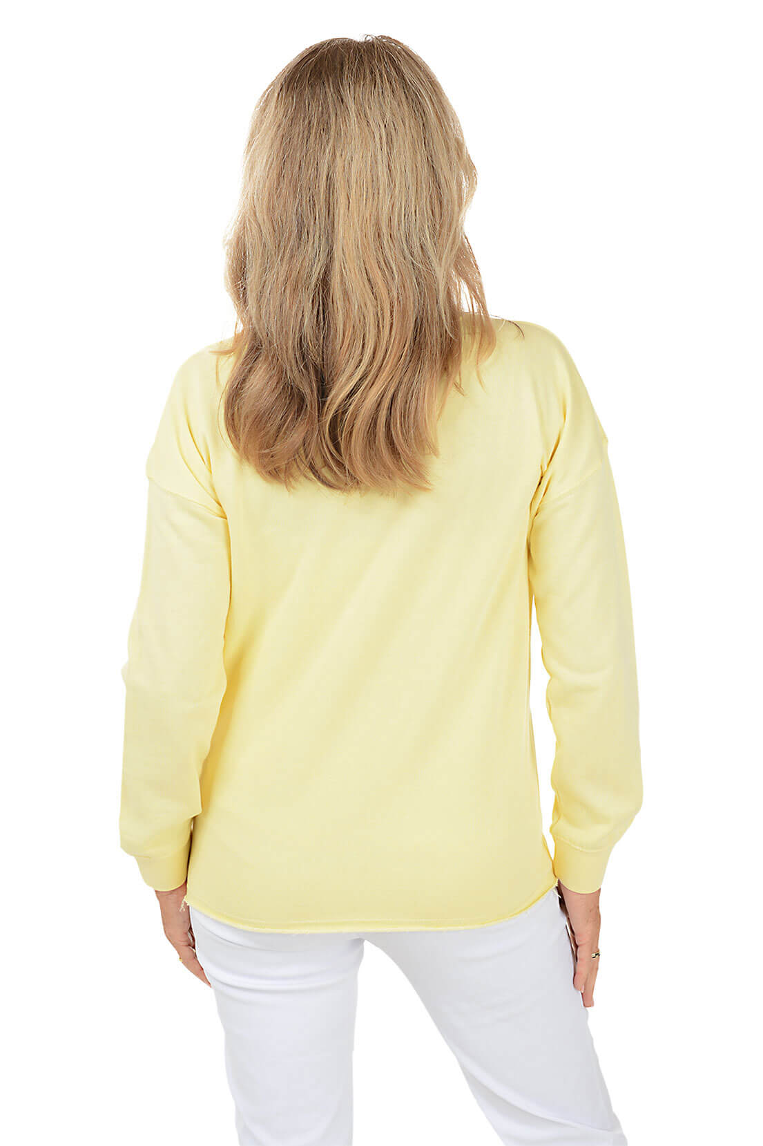 Person wearing a yellow sweater and white pants on a white background