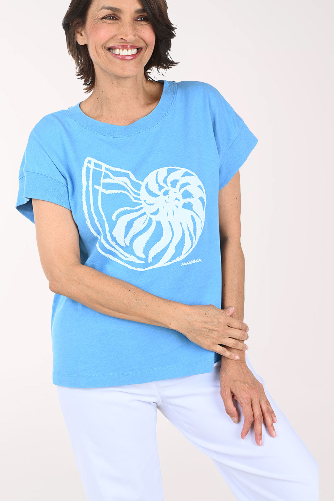 Woman wearing a light blue t-shirt with a white graphic design on a plain background