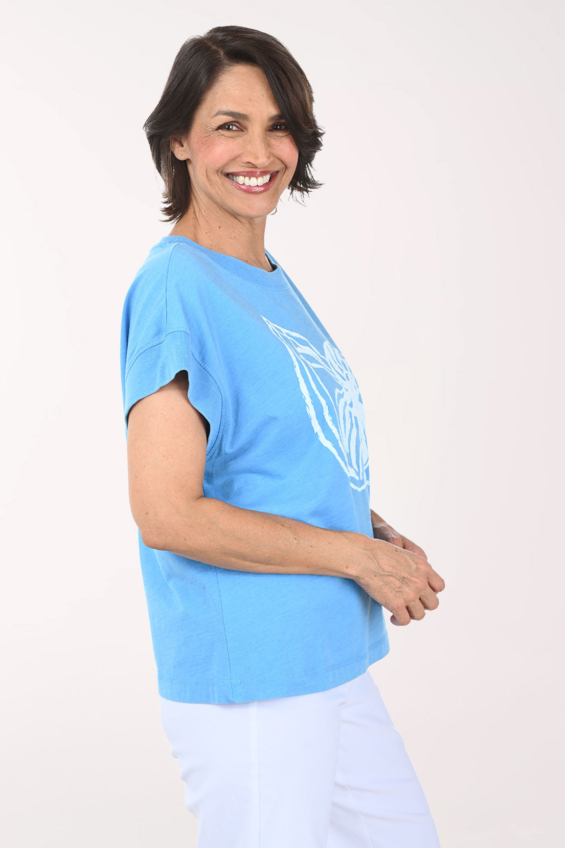 Woman wearing a light blue t-shirt with a white graphic design on a plain background