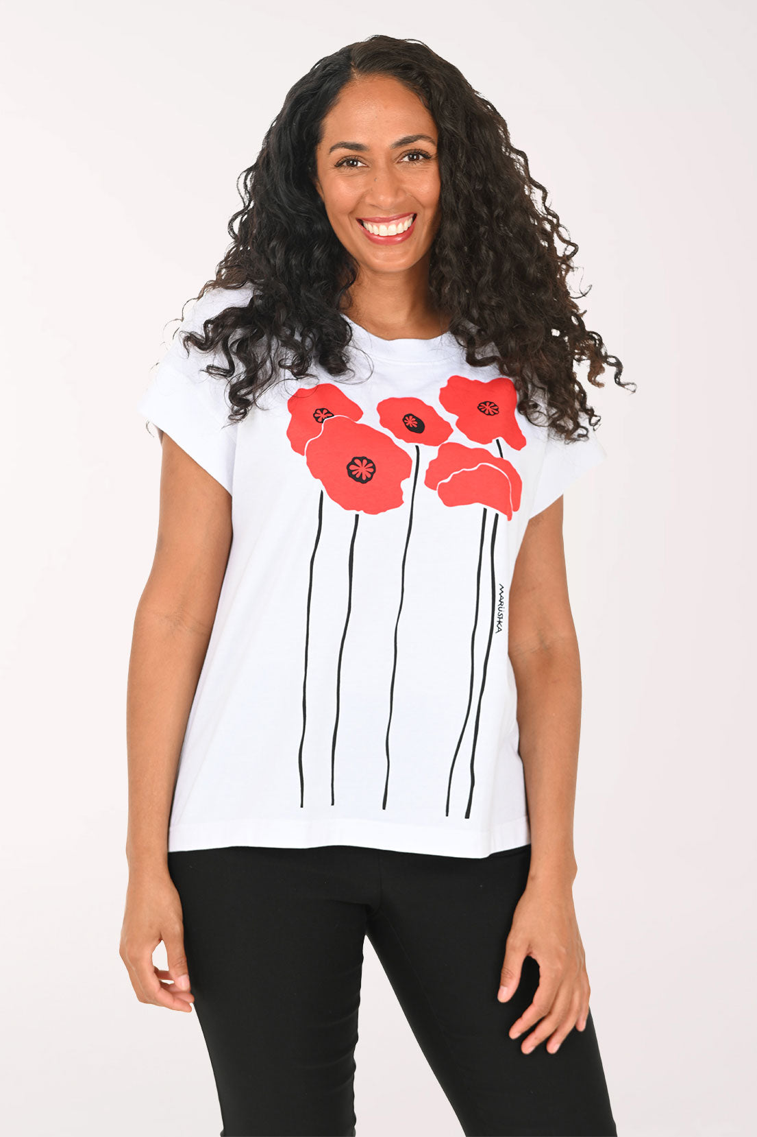 Woman wearing a white t-shirt with red floral designs on a plain background