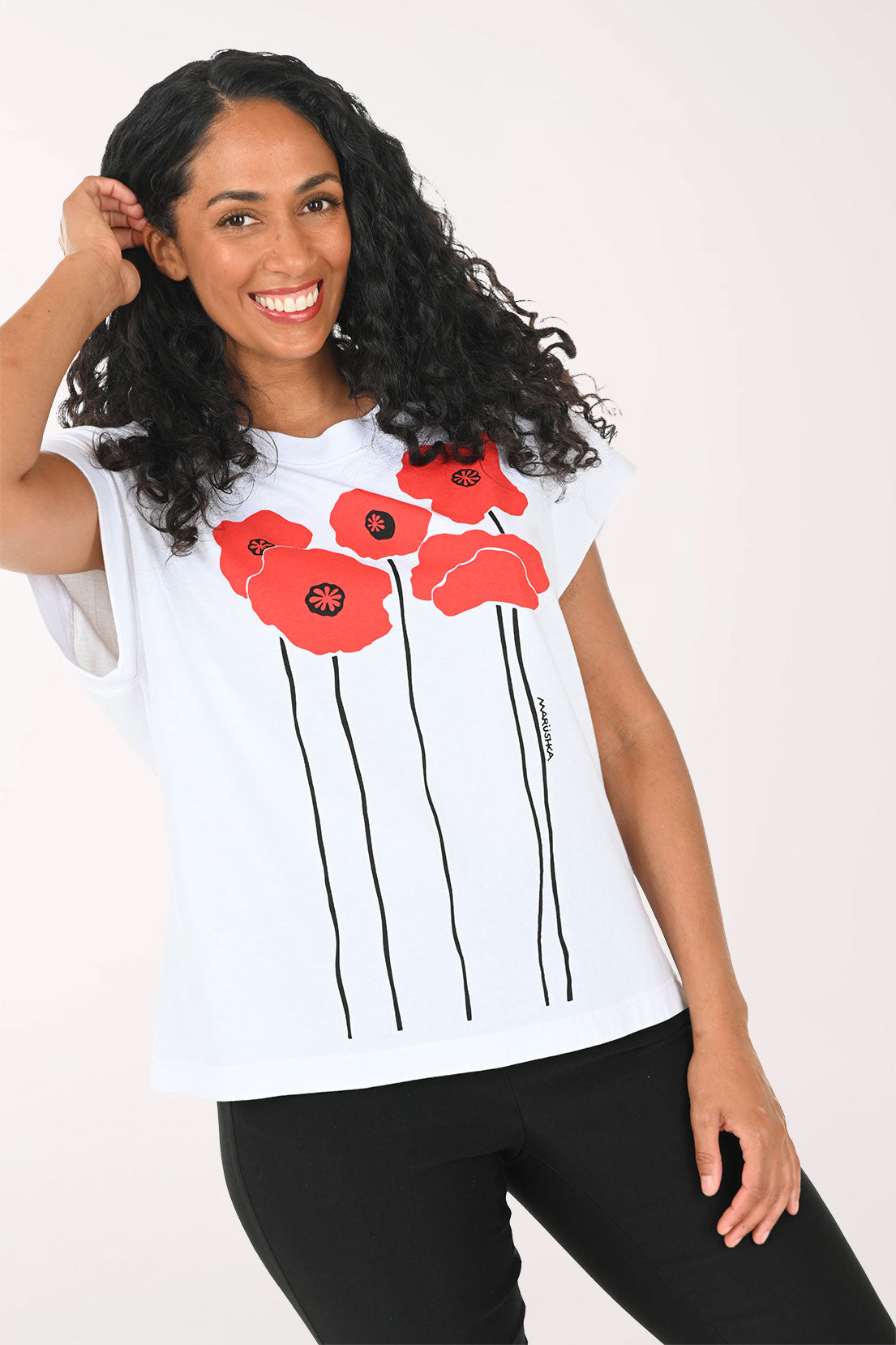 Woman wearing a white t-shirt with red floral designs on a plain background