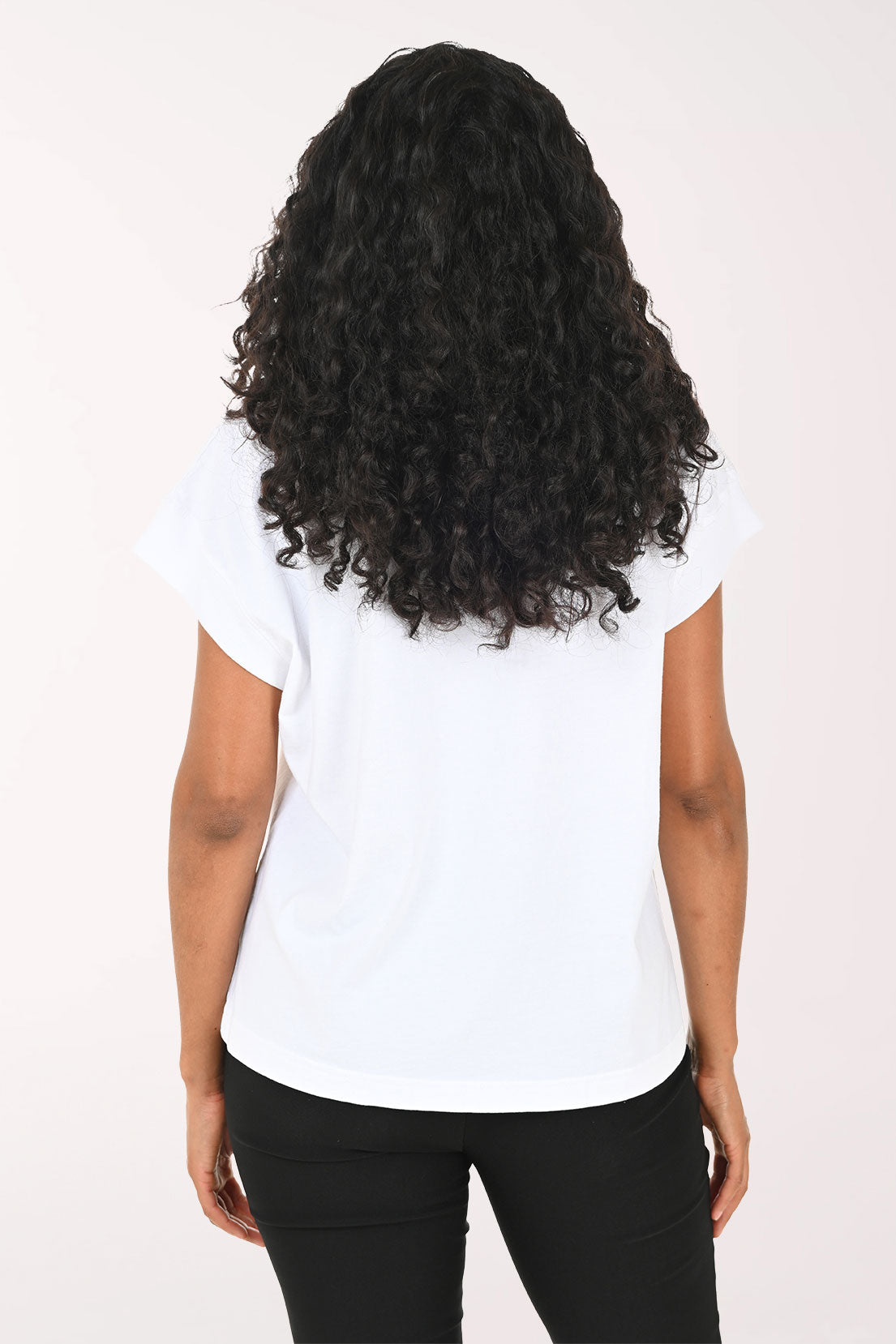 Woman wearing a white t-shirt with red floral designs on a plain background