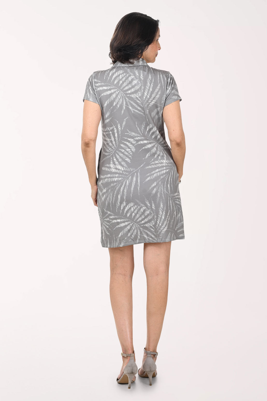Woman wearing a gray dress with leaf pattern on a white background