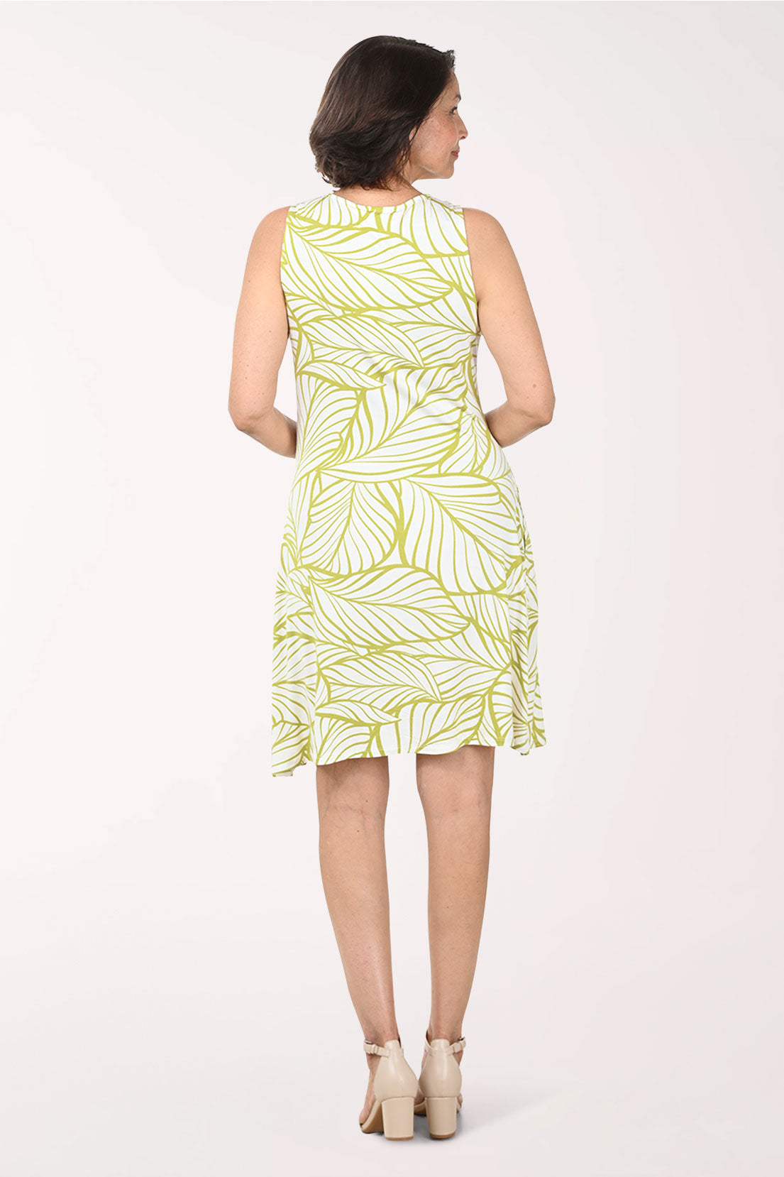 Woman wearing a sleeveless yellow dress with a palm print pattern