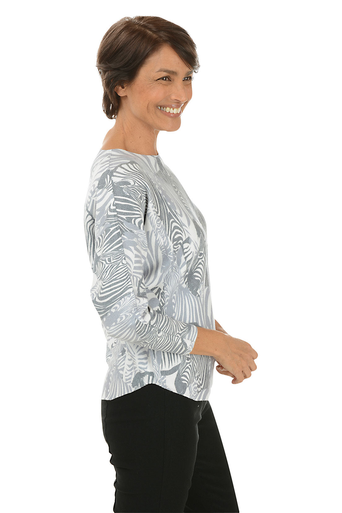 Woman wearing a grey and white zebra illustrated patterned long-sleeve top on a white background. Side shot.