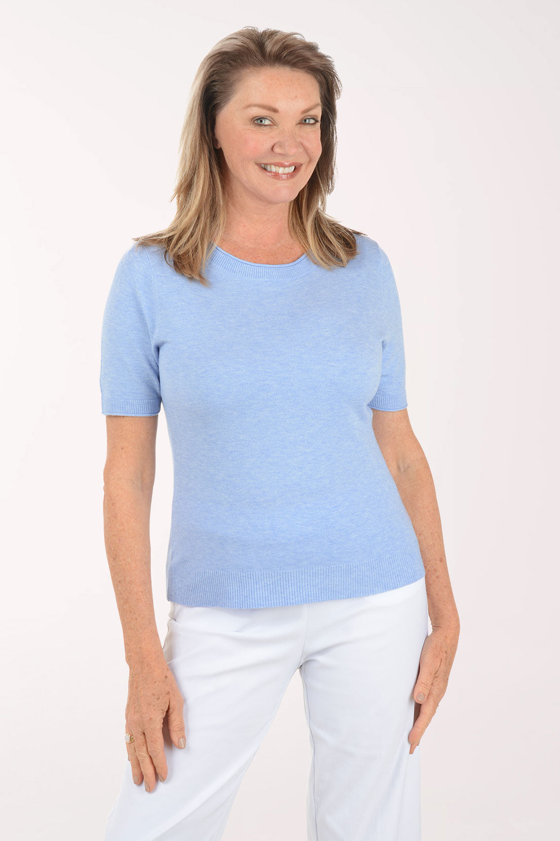Woman wearing a light blue t-shirt and white pants on a white background