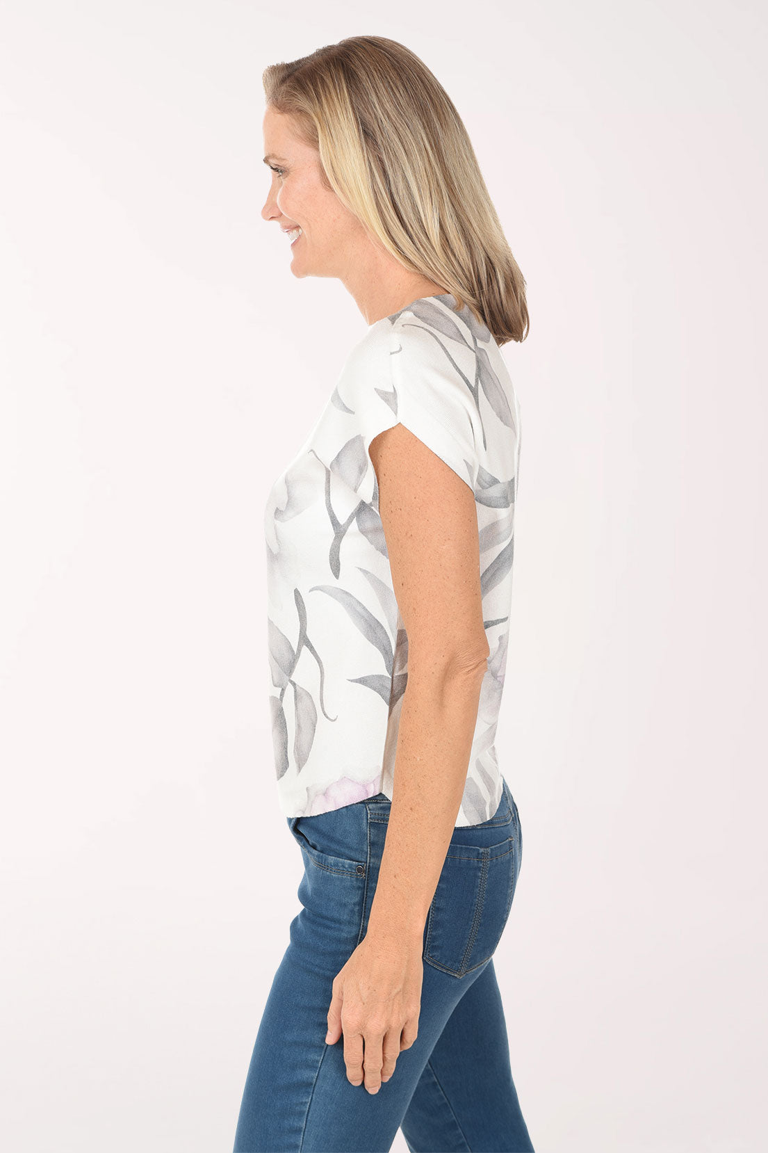 Woman wearing a white floral blouse with blue jeans on a white background