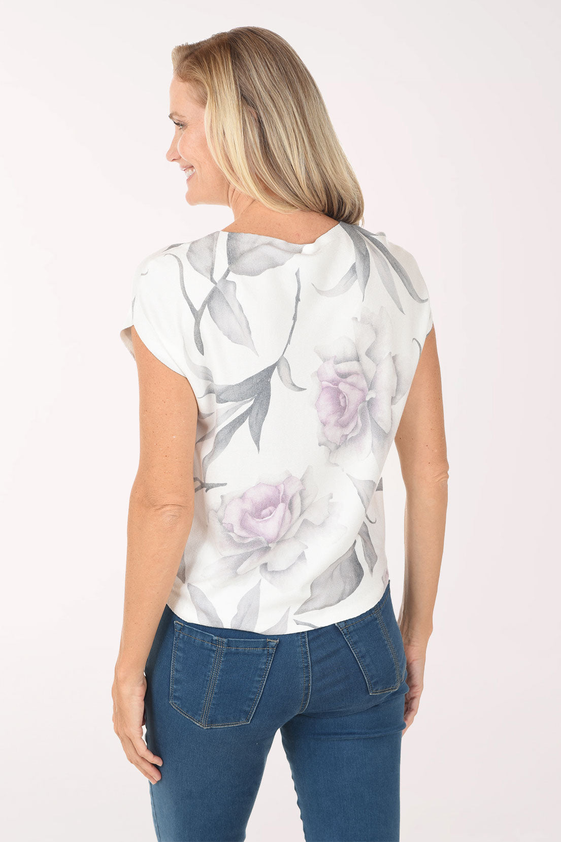 Woman wearing a white floral blouse with blue jeans on a white background