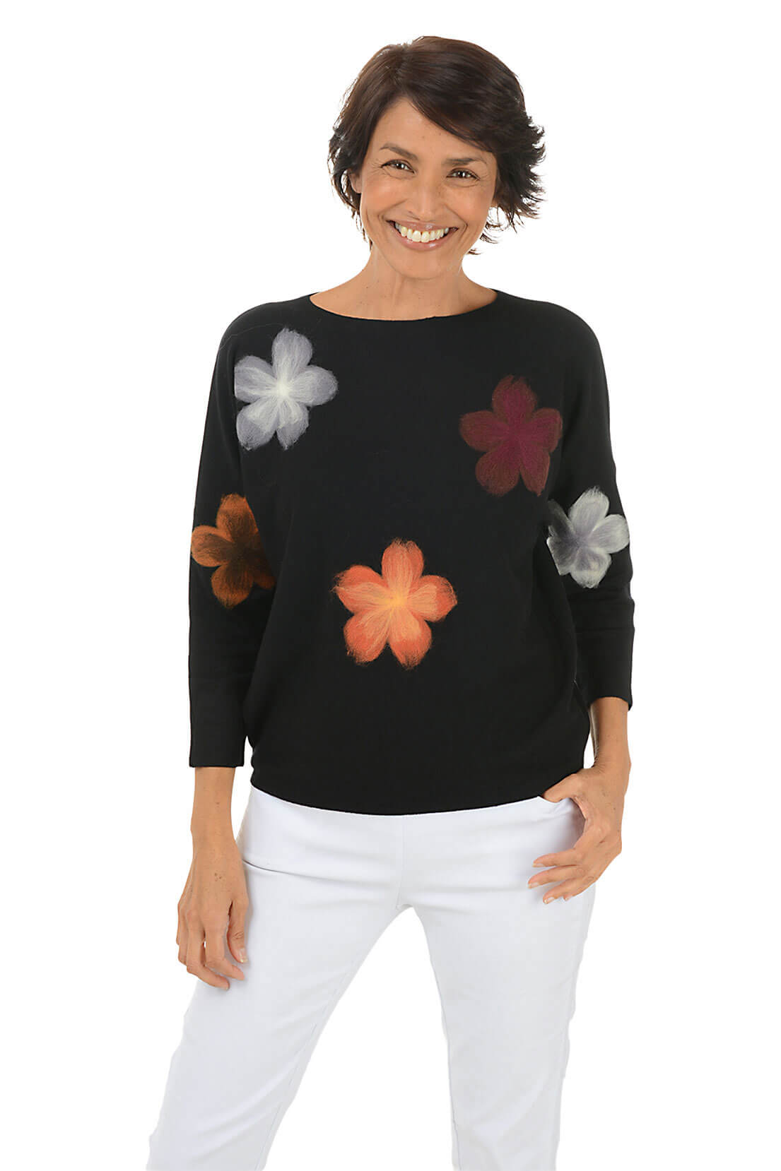 Woman wearing a black sweater with colorful flower patterns on a white background