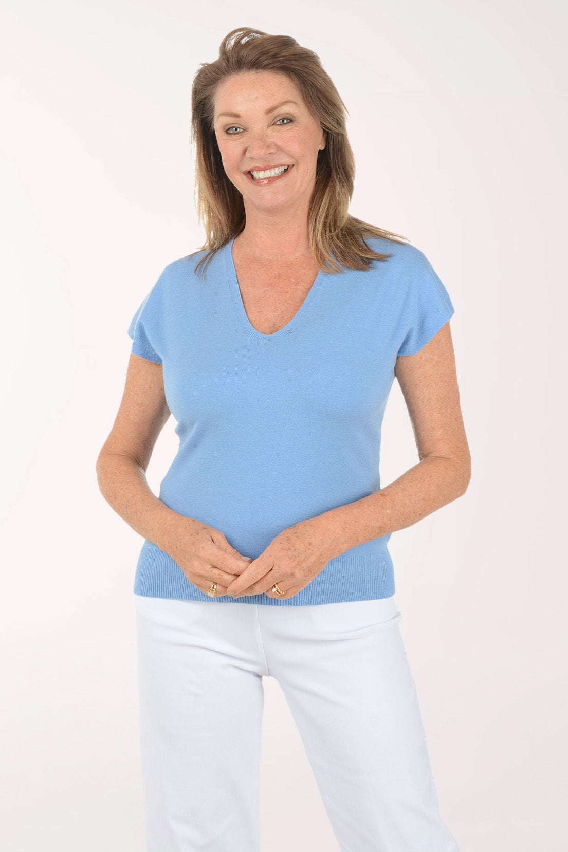 Woman wearing a light blue shirt and white pants on a white background