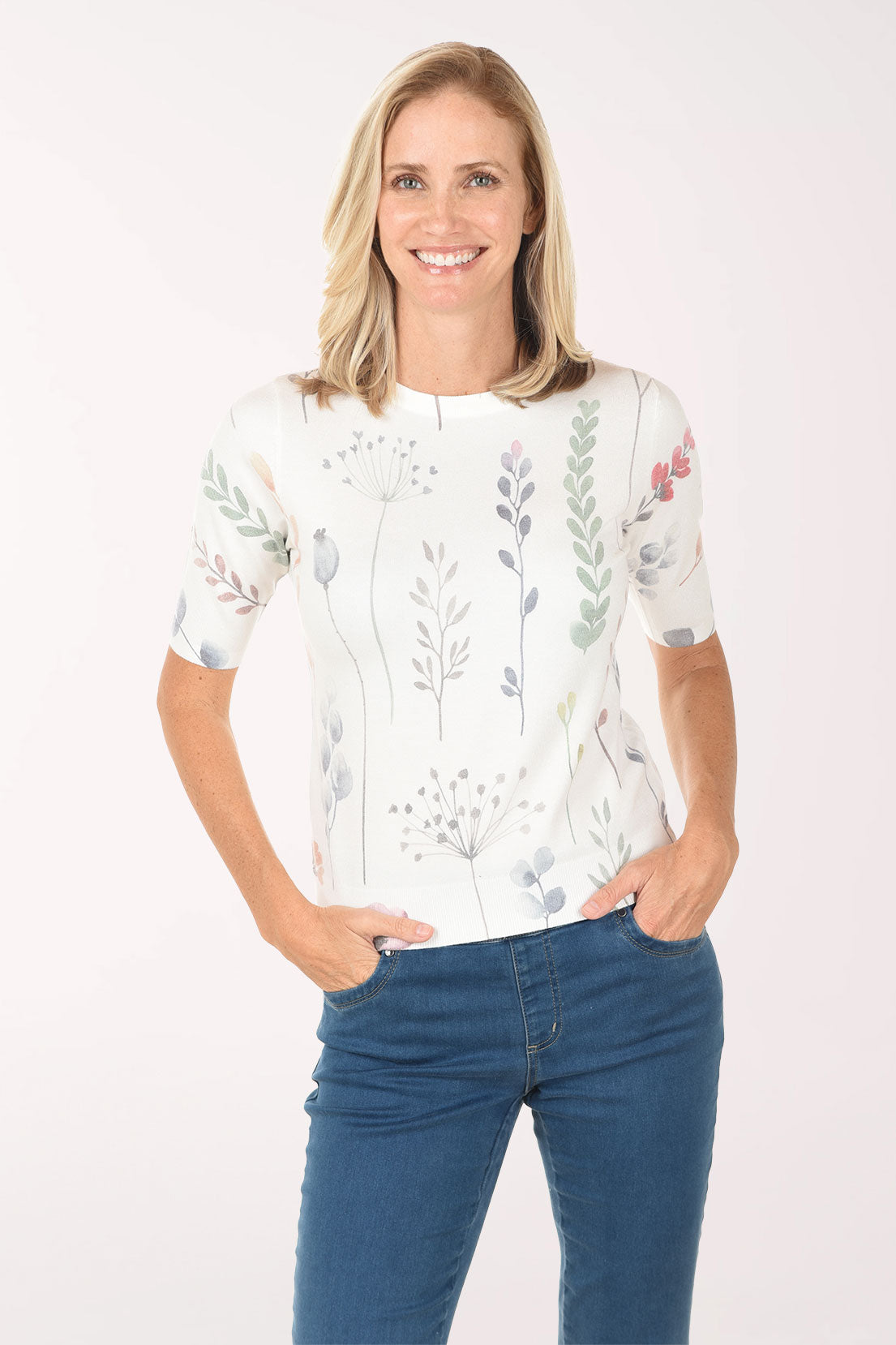 Woman wearing a white floral blouse and blue jeans on a white background
