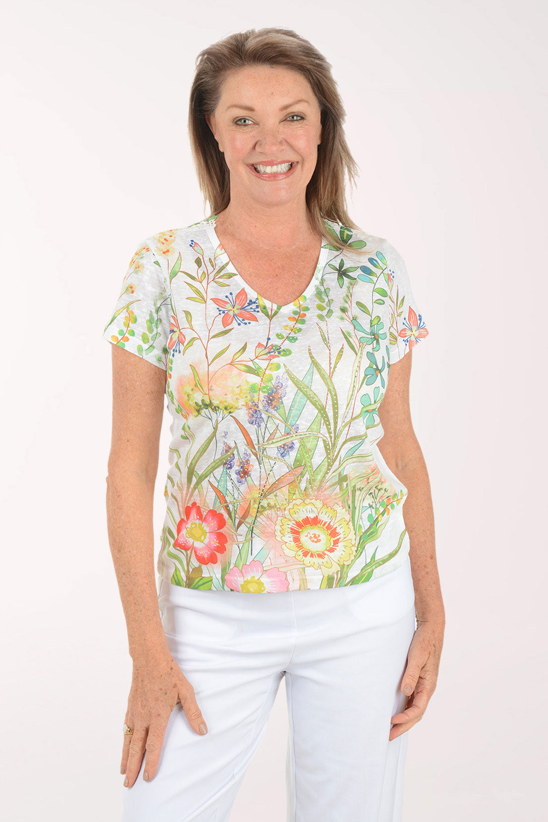 Woman wearing a floral blouse and white pants on a white background
