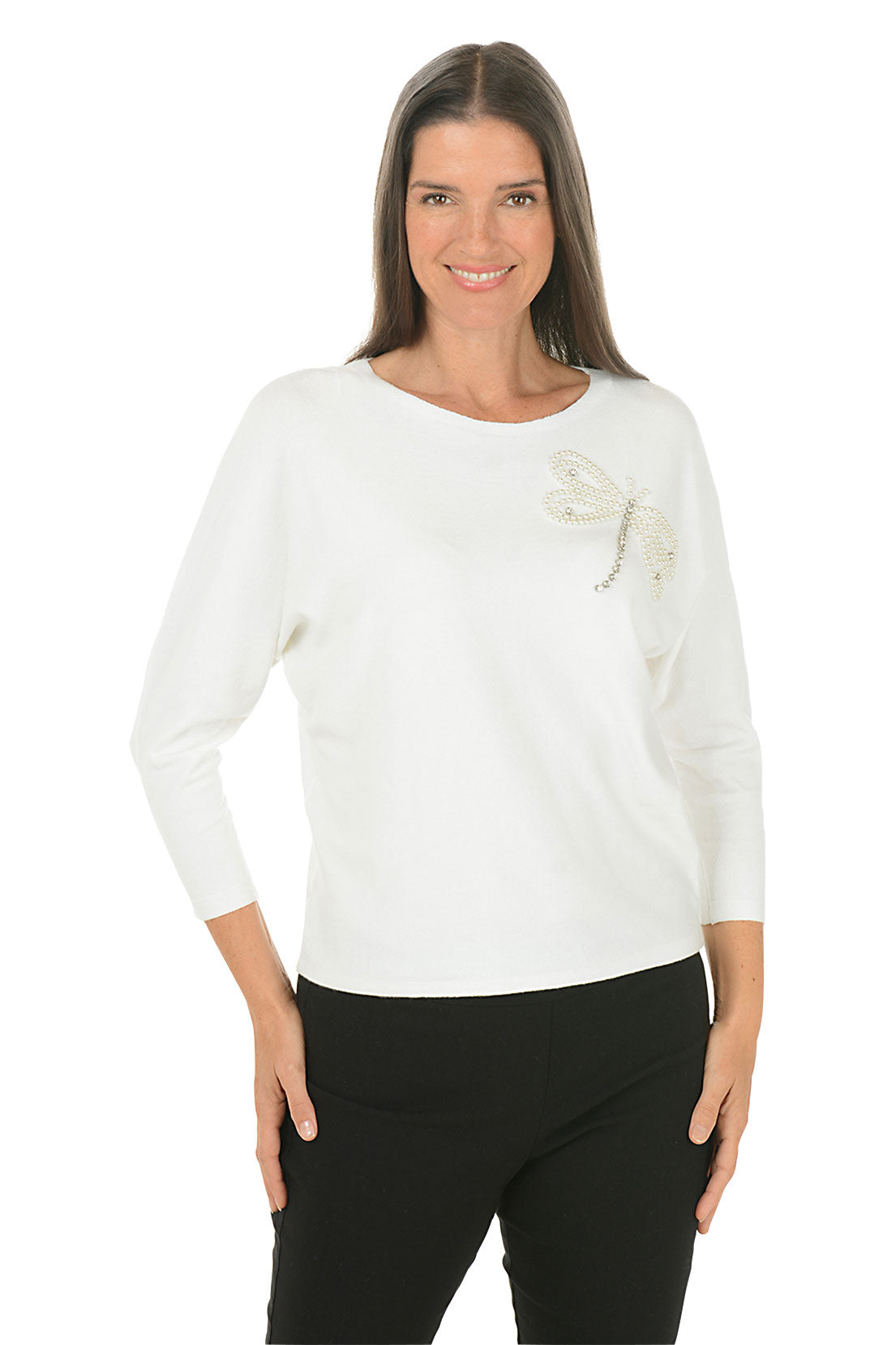 A woman wearing a white 3/4 sleeve sweater with a jeweled dragonfly detail.