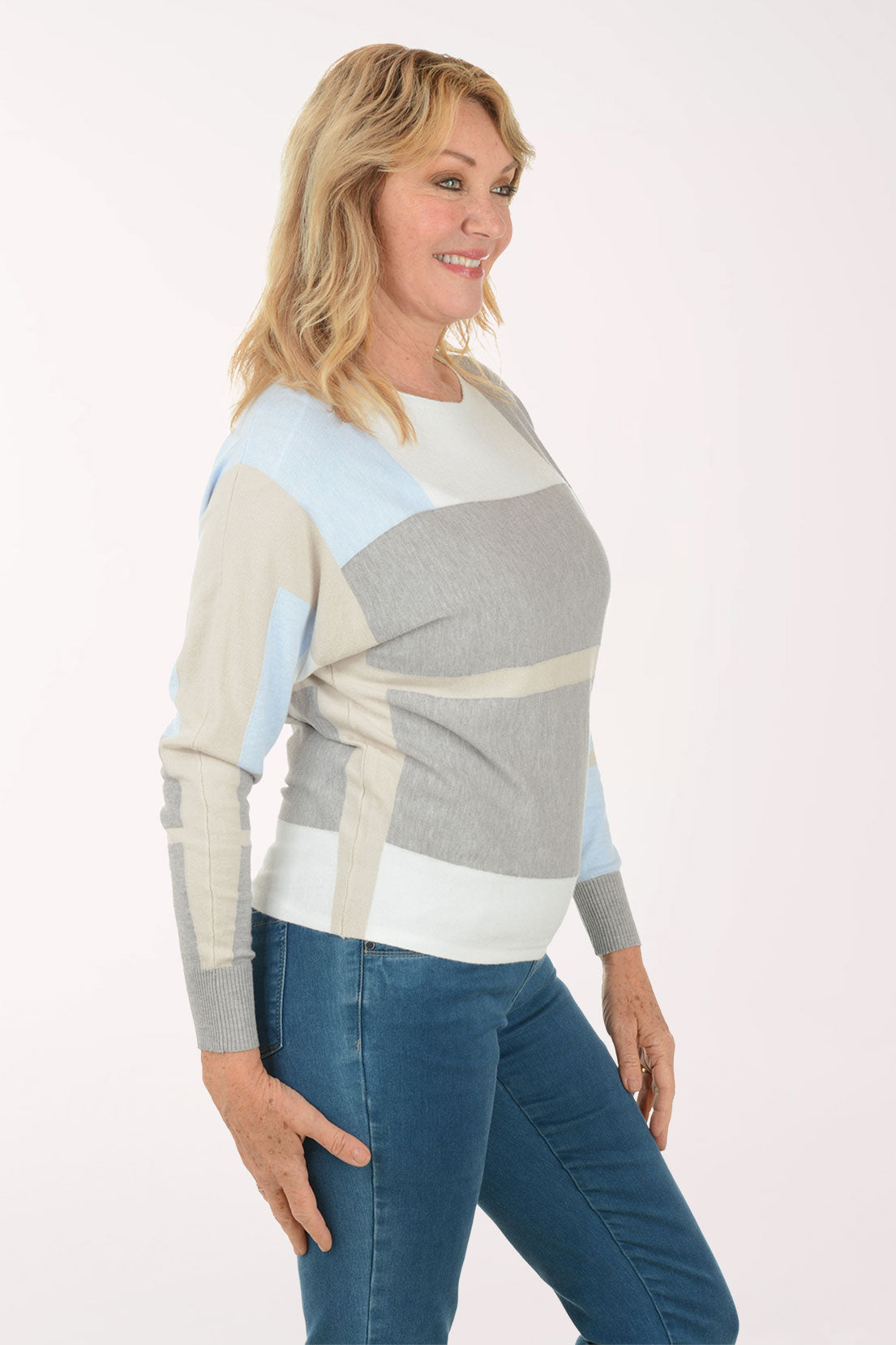 Woman wearing a color-blocked sweater and jeans on a white background