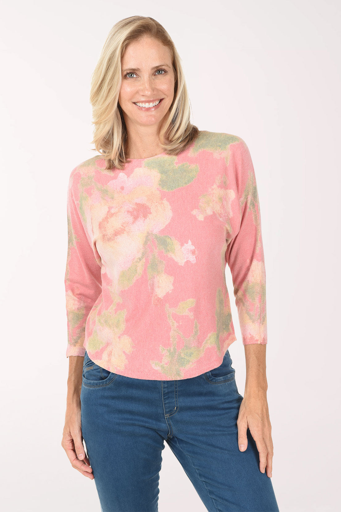 Woman wearing a pink tie-dye shirt and blue jeans on a white background