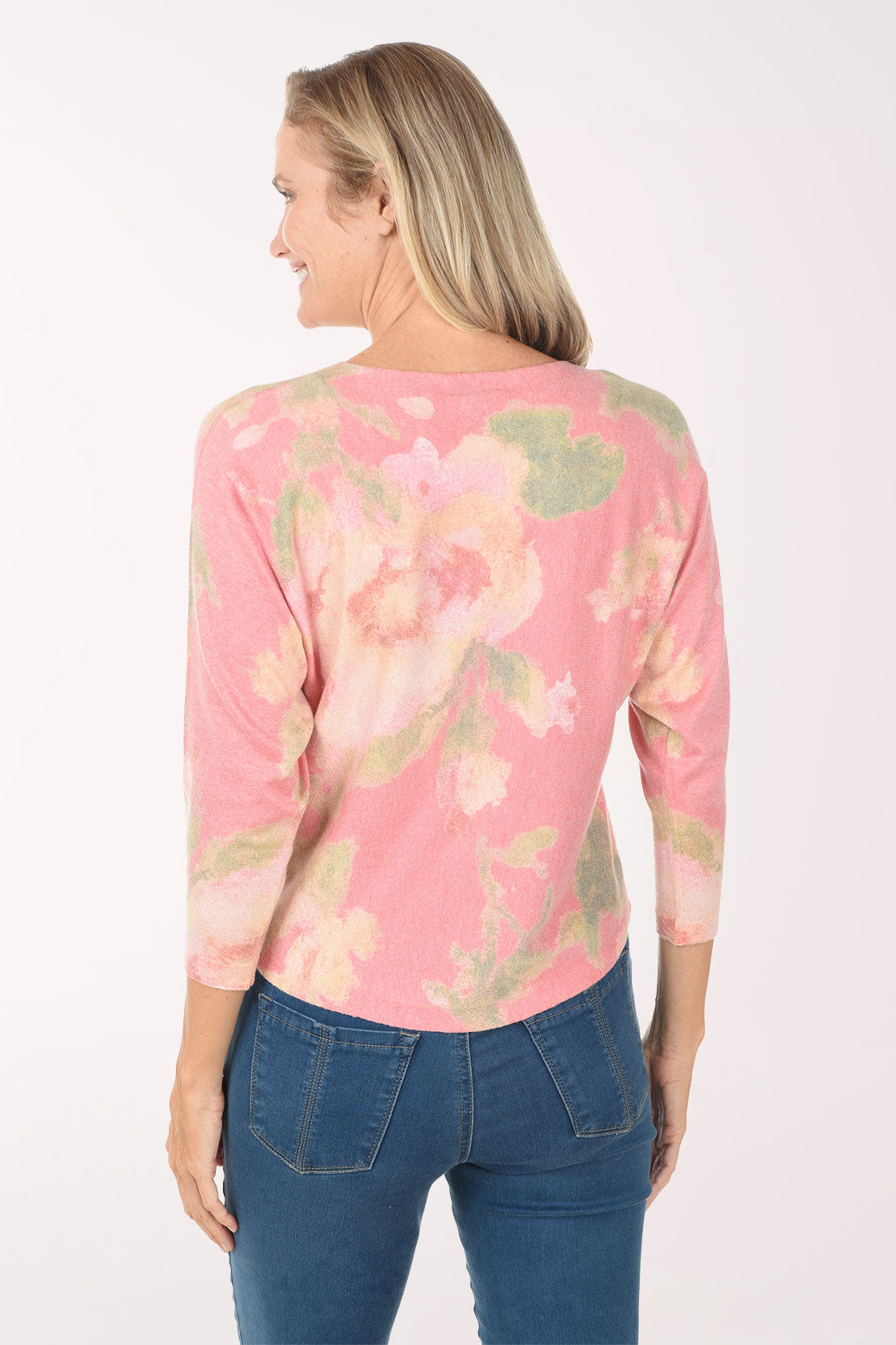 Woman wearing a pink tie-dye shirt and blue jeans on a white background