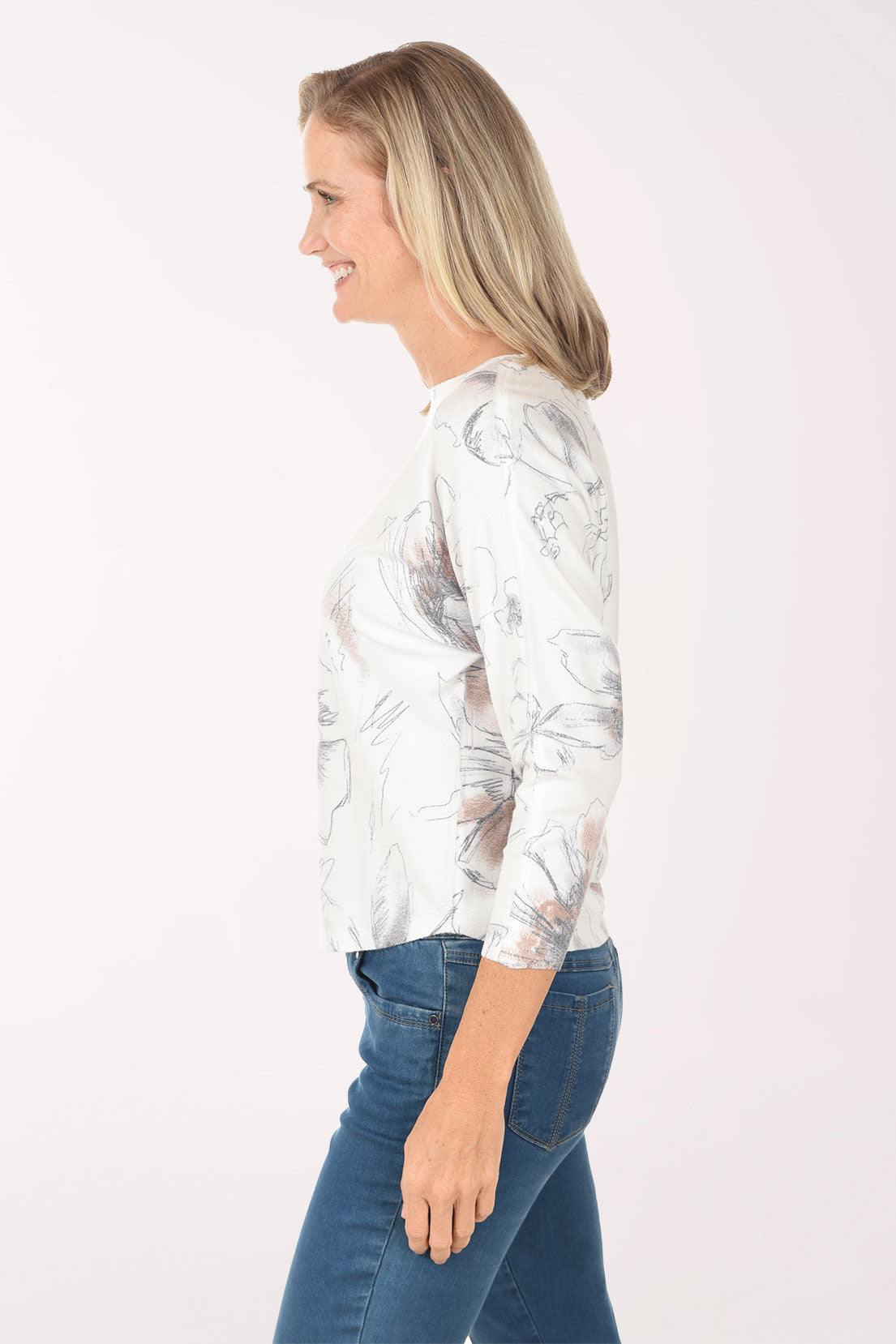 Woman wearing a floral blouse and blue jeans on a white background