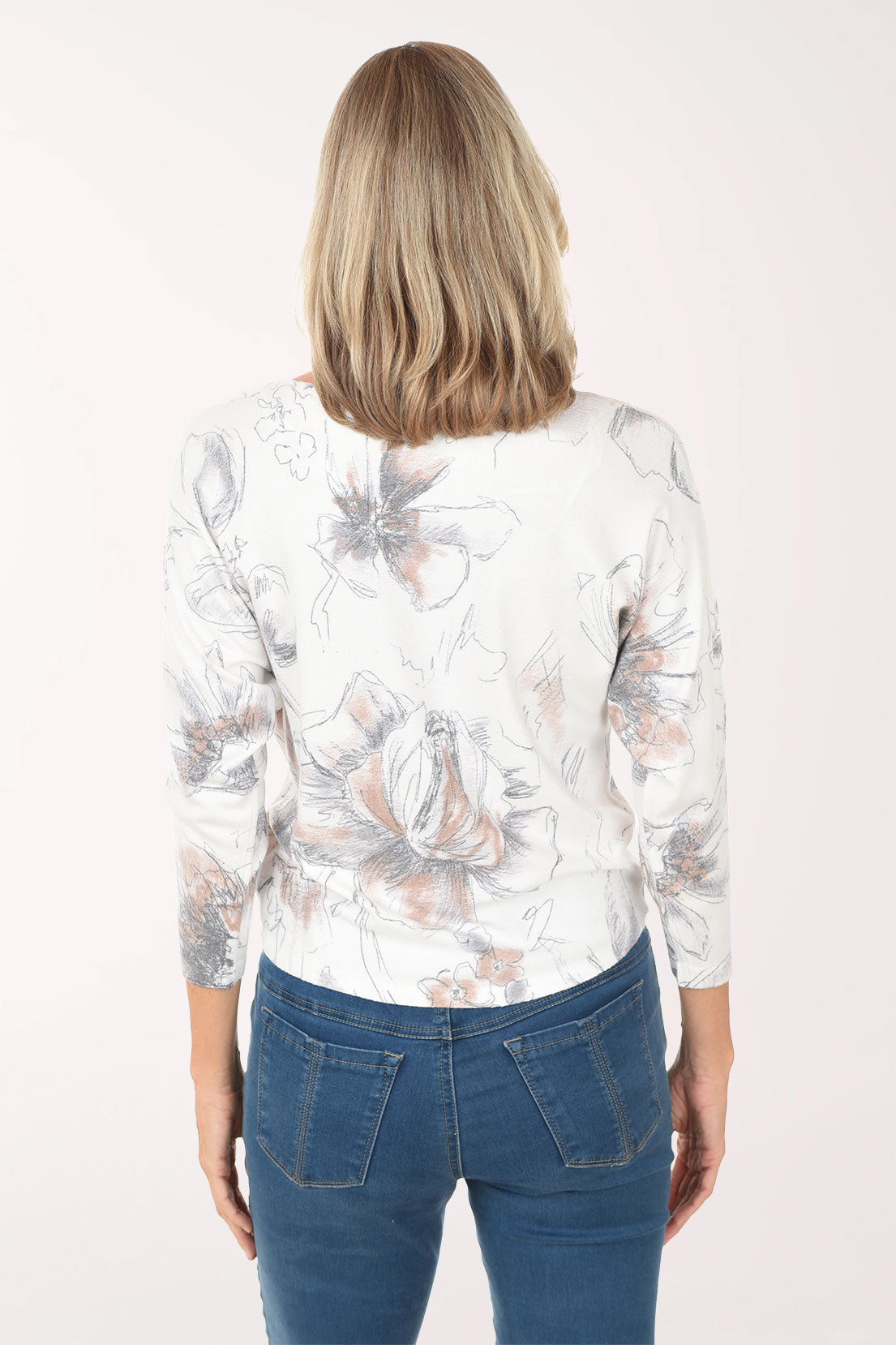 Woman wearing a floral blouse and blue jeans on a white background