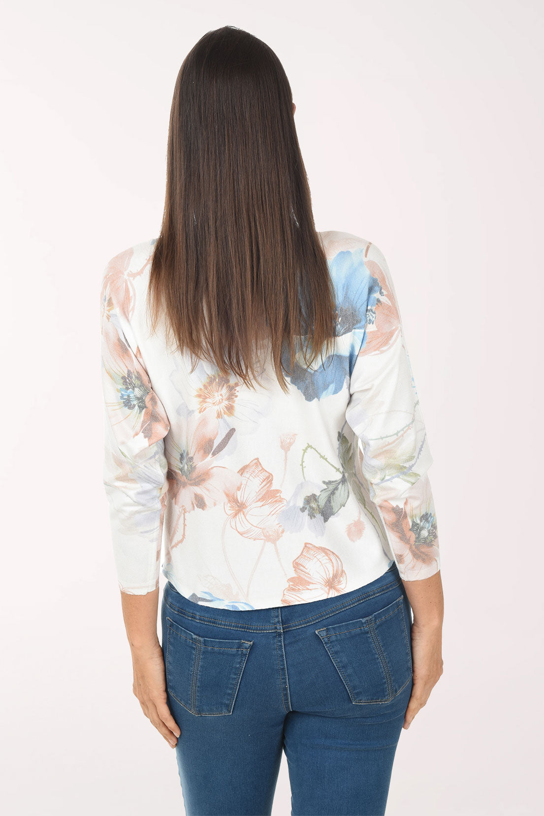 Woman wearing a floral blouse and blue jeans on a white background