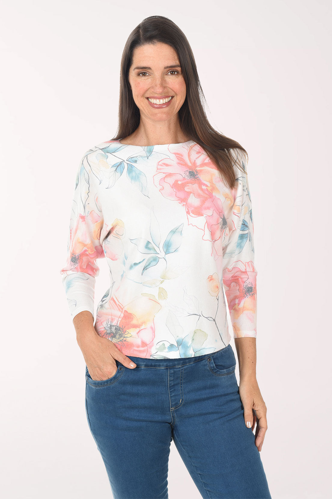 Woman wearing a floral long-sleeve top and blue jeans on a white background