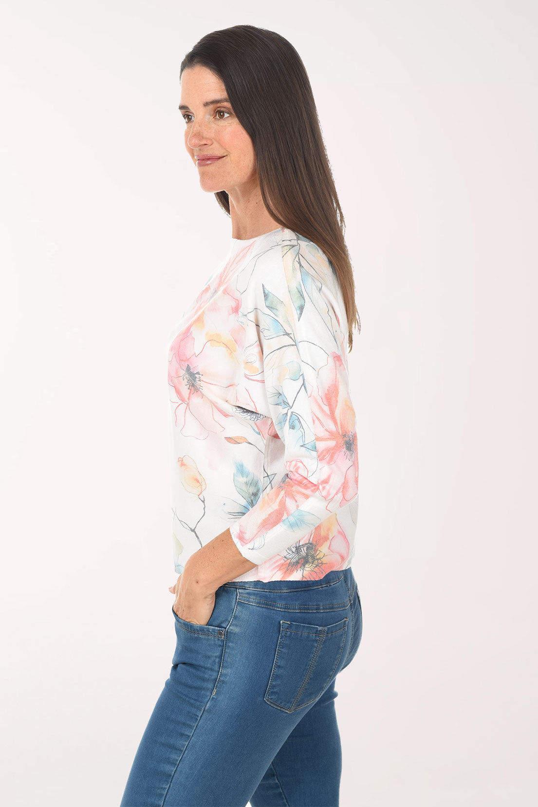 Woman wearing a floral long-sleeve top and blue jeans on a white background