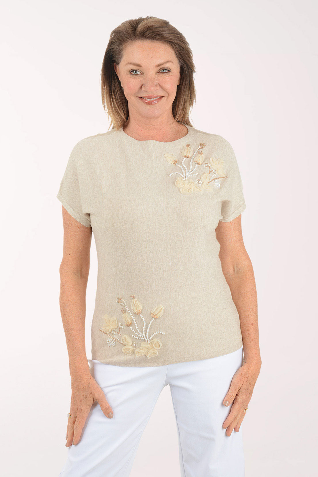 Woman wearing a beige t-shirt with floral embroidery on a white background