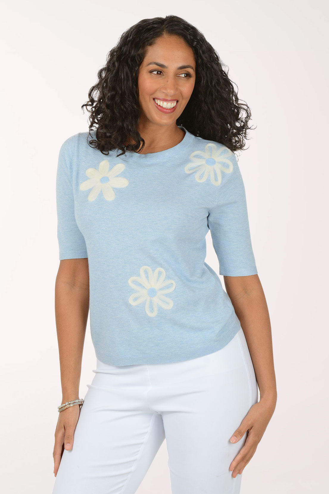 Woman wearing a light blue sweater with floral patterns on a white background