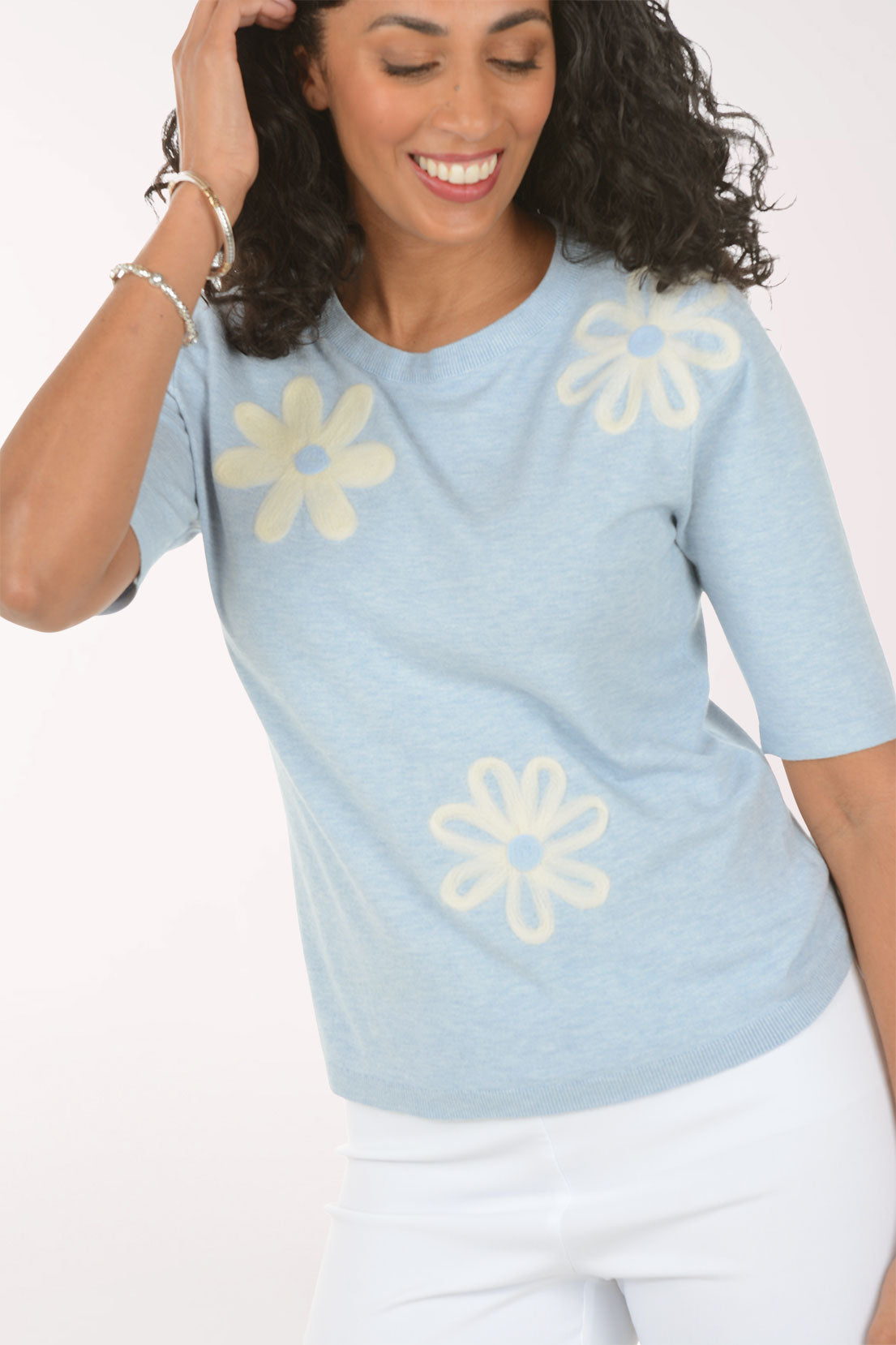 Woman wearing a light blue sweater with yellow flower patterns on a white background