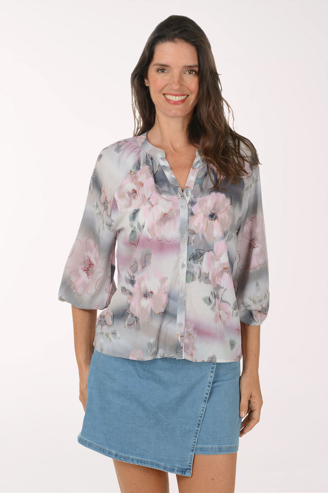 Woman wearing a floral blouse and denim skirt on a white background