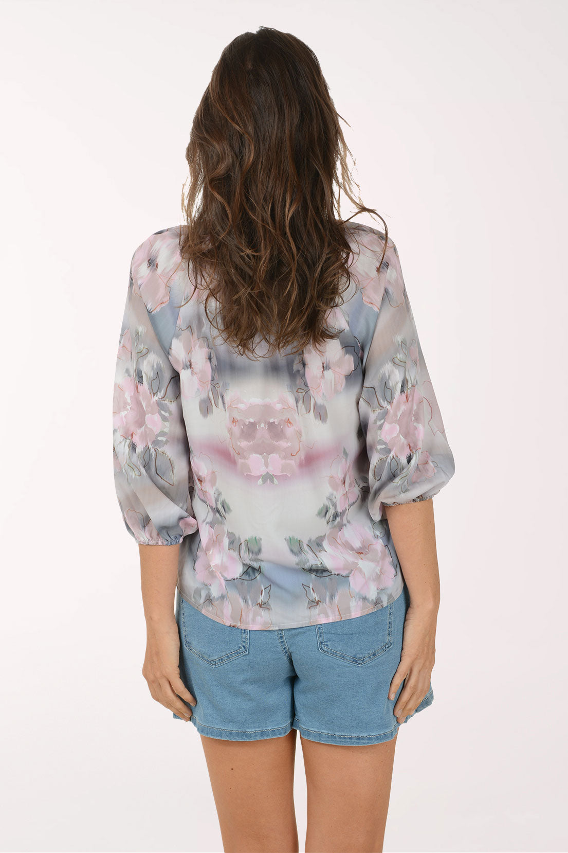 Woman wearing a floral blouse and denim skirt on a white background