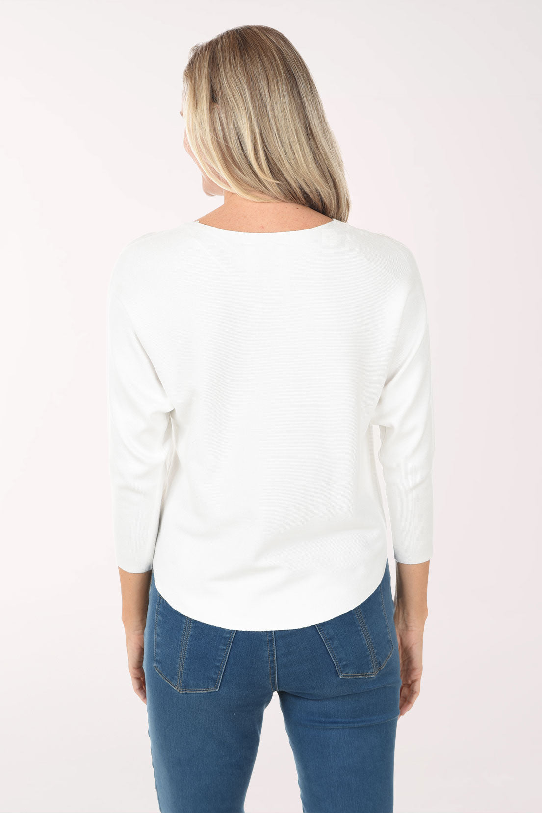 Woman wearing a white top with blue floral patterns on a plain background