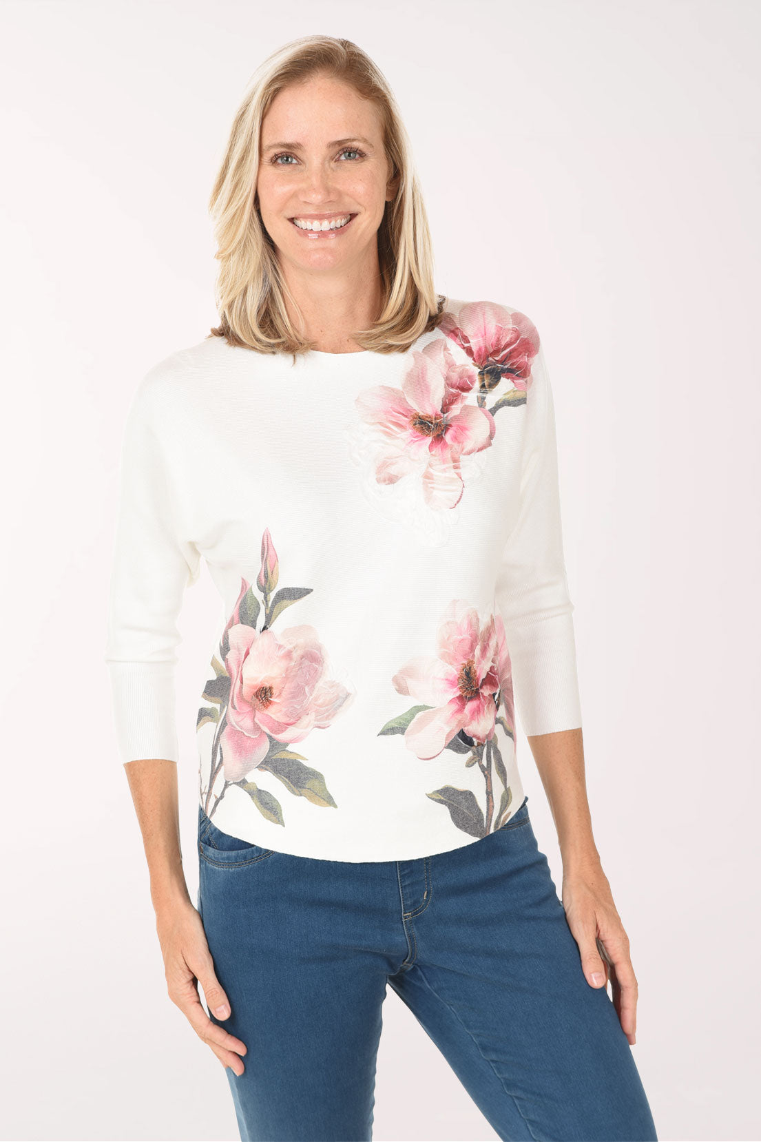Woman wearing a white sweater with pink floral patterns on a white background